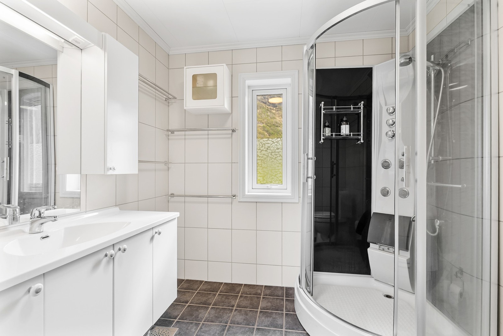 Badet har flislagt gulv med varmekabler, dusjkabinett, wc og servantinnredning. Galleribilde