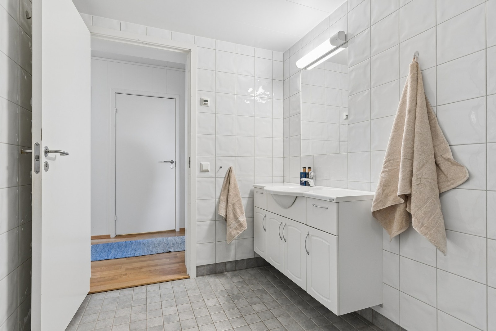 Badet er flislagt med grå gulvfliser og hvite veggfliser. Det er også opplegg for vaskemaskin Galleribilde