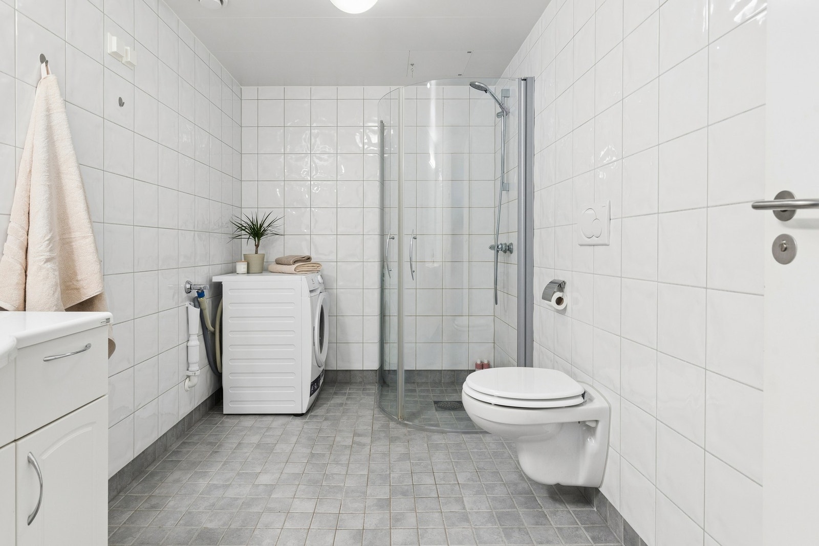 Det er utstyrt med dusjhjørne med buede, innsvingbare glassdører, vegghengt toalett, baderomsinnredning med heldekkende servant og speil. Galleribilde