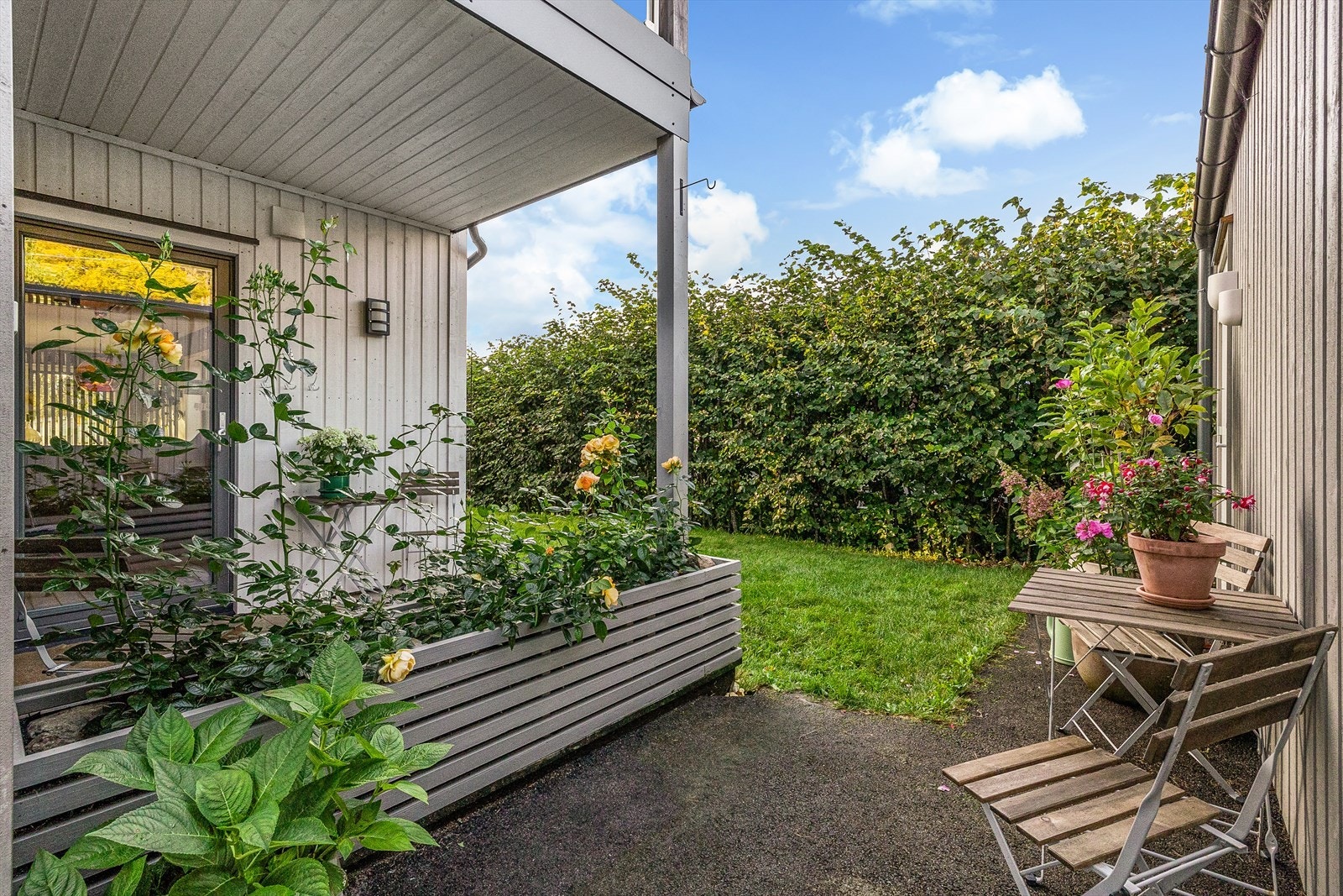Ved veggen til carporten er det etablert en hyggelig uteplass som skaper en lun og skjermet sone for avslapning og hyggelige stunder utendørs. Galleribilde