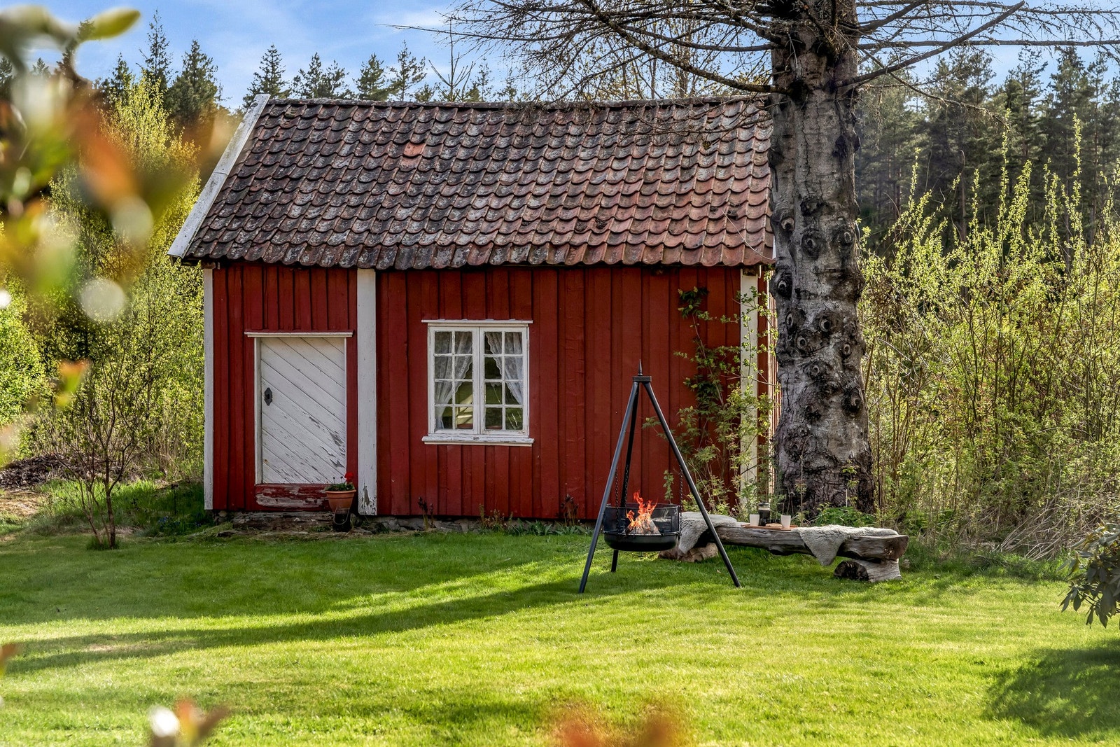 På baksiden av garasjen har man en koselig plass med tilgang til tømmerhytten/stabburet fra 1800-tallet Galleribilde