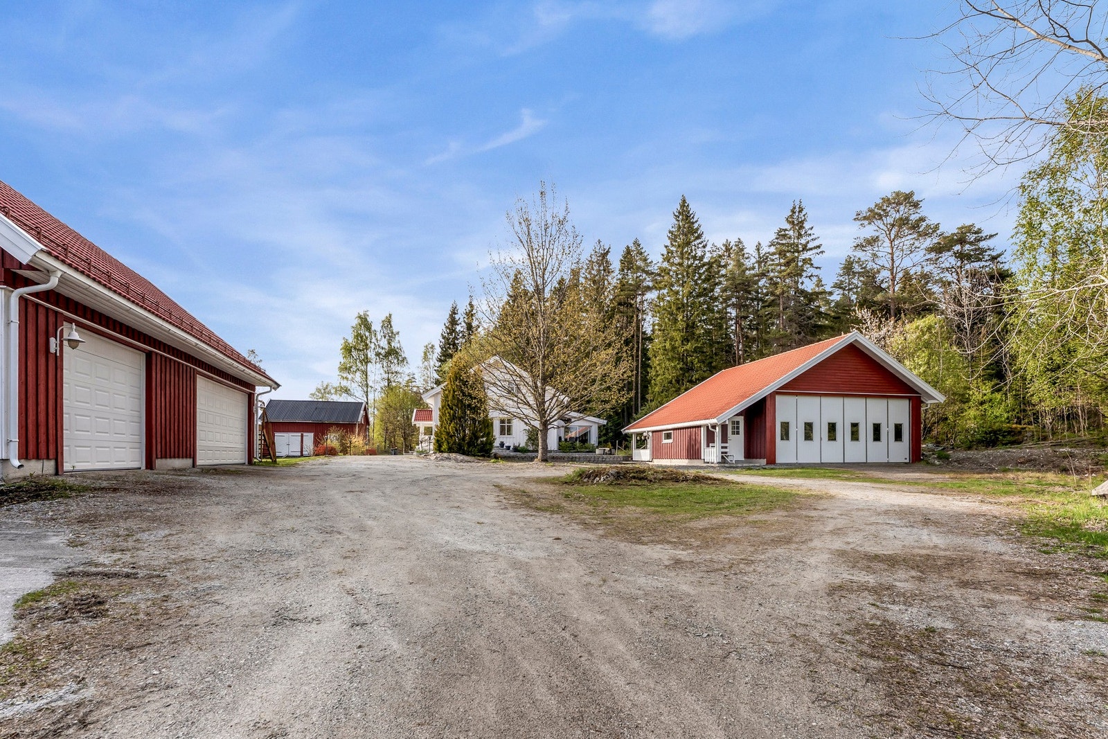 Stor gårdsplass med egen og praktisk rundkjøring. Her har man først tilgang til store garasjer fra hhv 2007 og 2009. Ene med stor takhøyde for maskiner, bobil, båt mm. Galleribilde