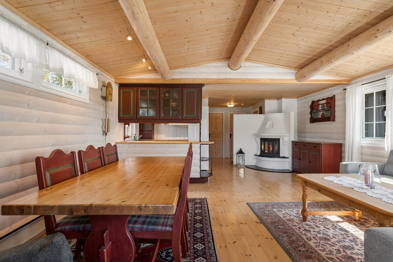 En hvitmalt elementpeis skaper hygge, mens taket med synlige åsstokker gir rommet karakter. Galleribilde