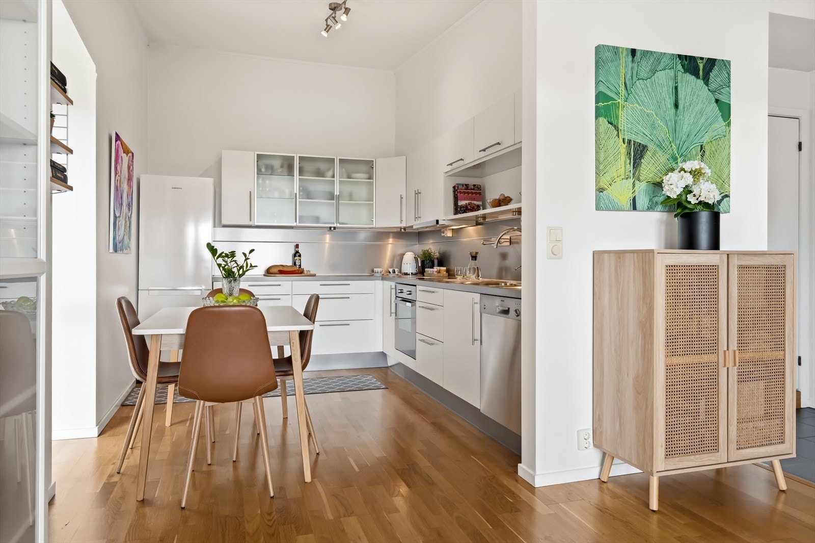 Kjøkkenet er utført med lys innredning bestående av hvite, glatte fronter og laminert benkeplate som gir et moderne og tidløst uttrykk. Galleribilde