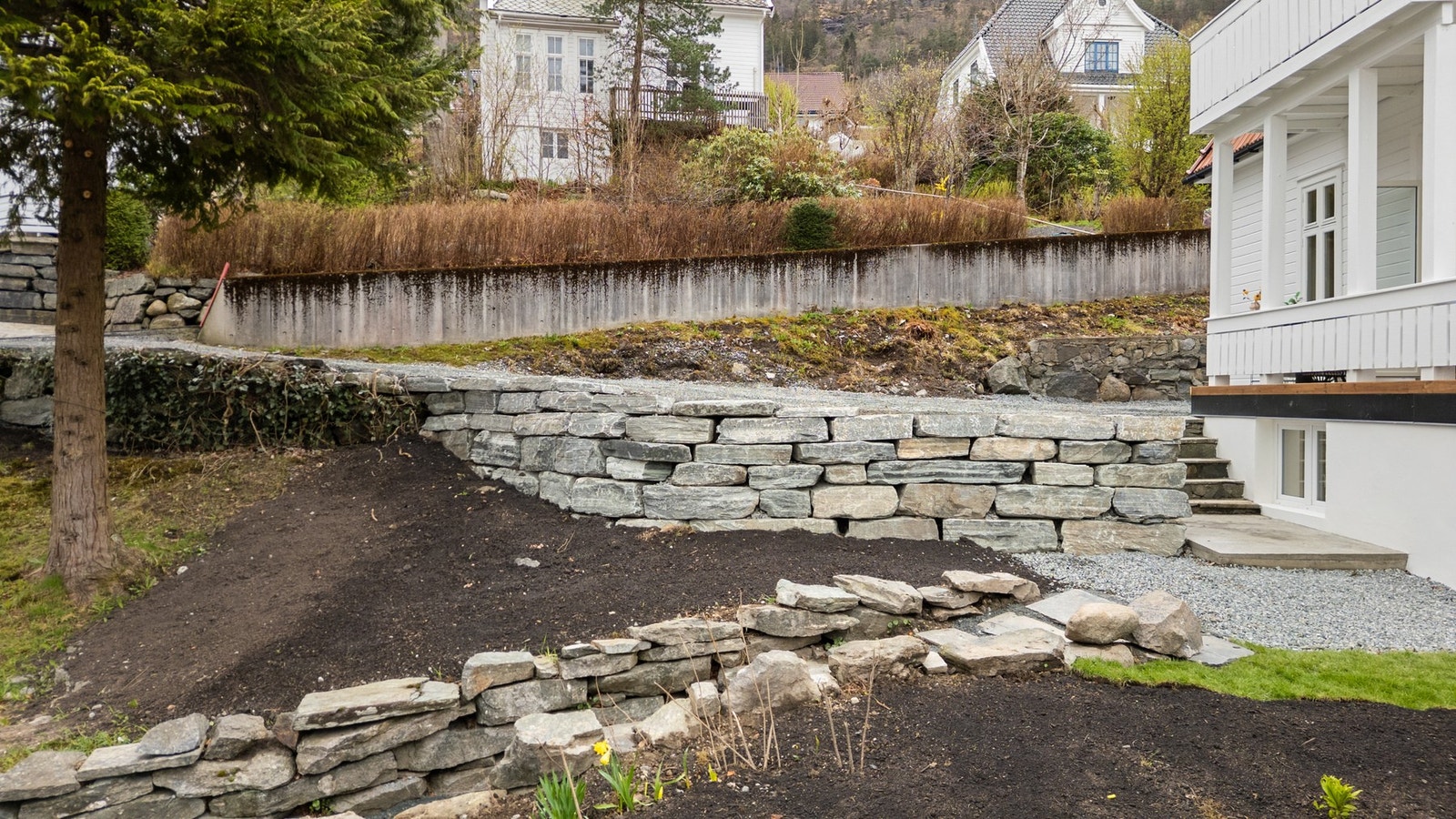 Pent opparbeidet med natursteinsmurer, gangtraseer og fin beplantning Galleribilde