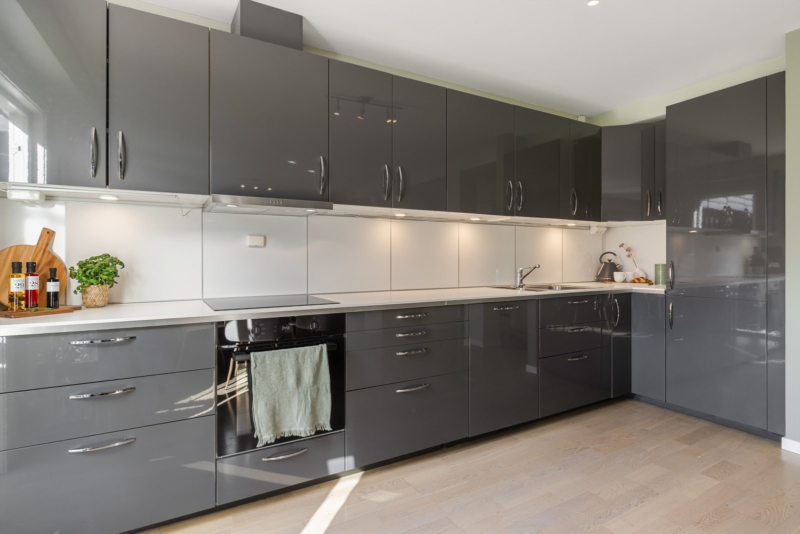 Innredningen har grå glatte fronter og laminert benkeplate med nedfelt oppvasskum. Praktisk med lyse plater i benkeryggen og belysning under overskapene. Galleribilde