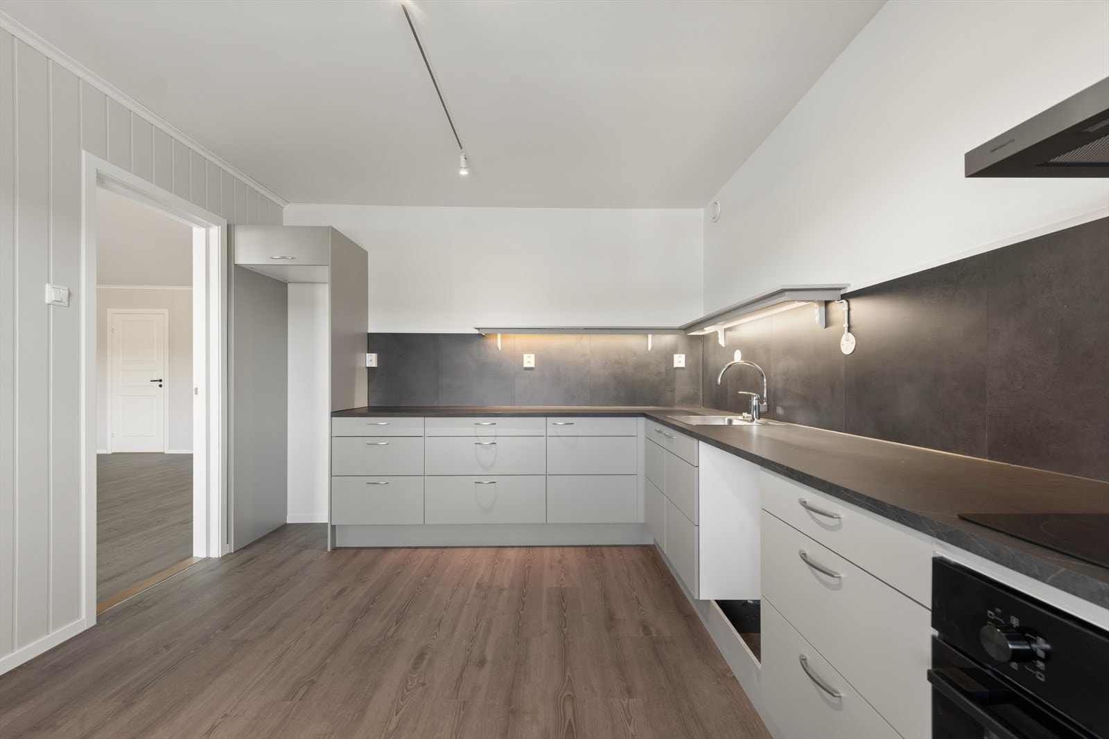 Kjøkkenet har en praktisk vinkelinnredning med slette fronter, laminatbenkeplate og kitchen board over arbeidsflatene. Galleribilde