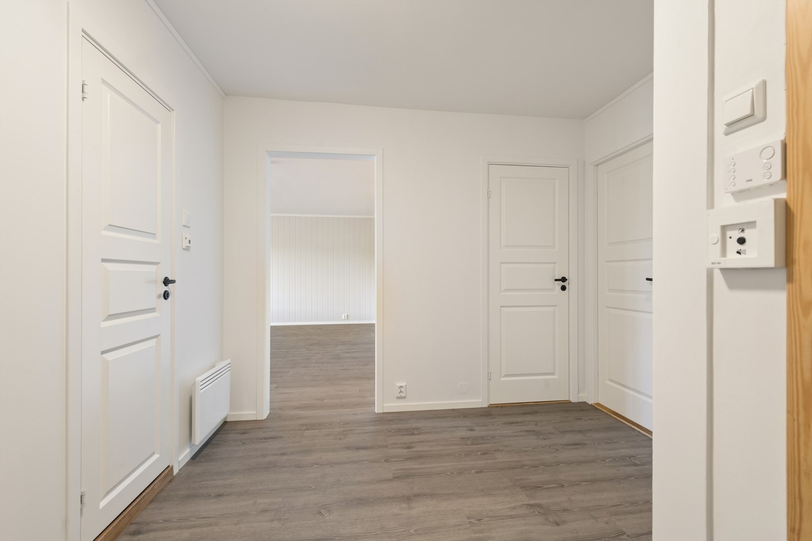 Entréen ønsker velkommen med gjennomgående laminatgulv og fabrikkmalte, formpressede speildører. Galleribilde