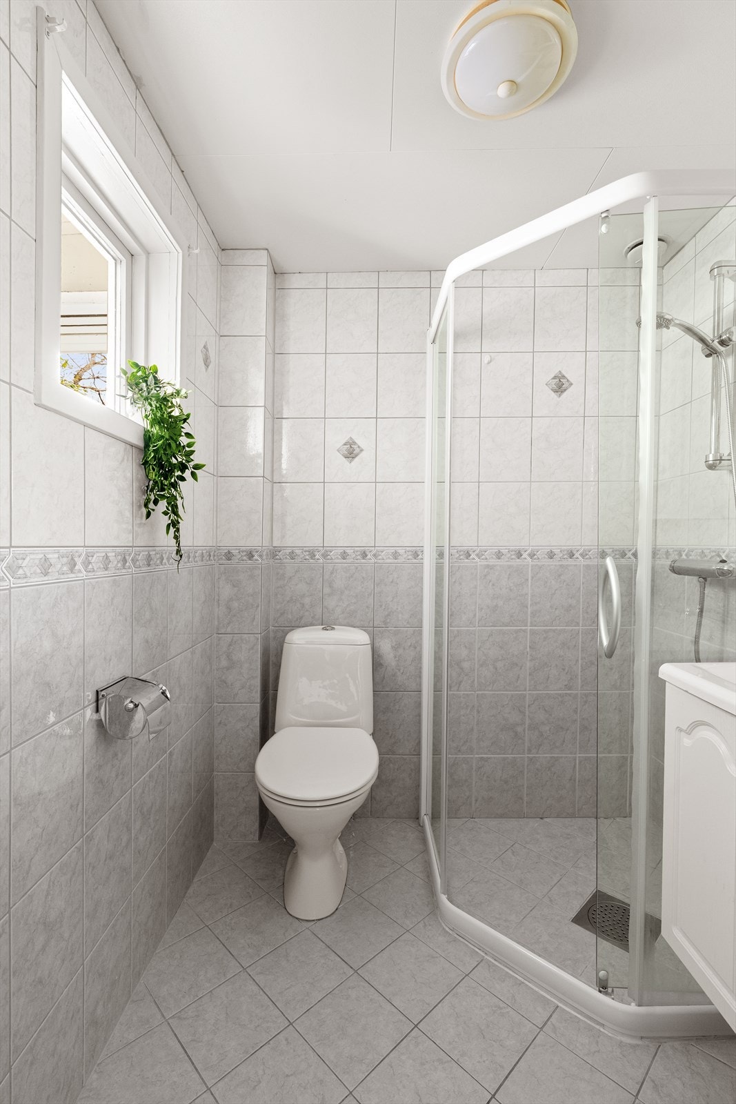 Badet i første etasje er flislagt og utstyrt med toalett, servant med innredning og dusjhjørne. Galleribilde