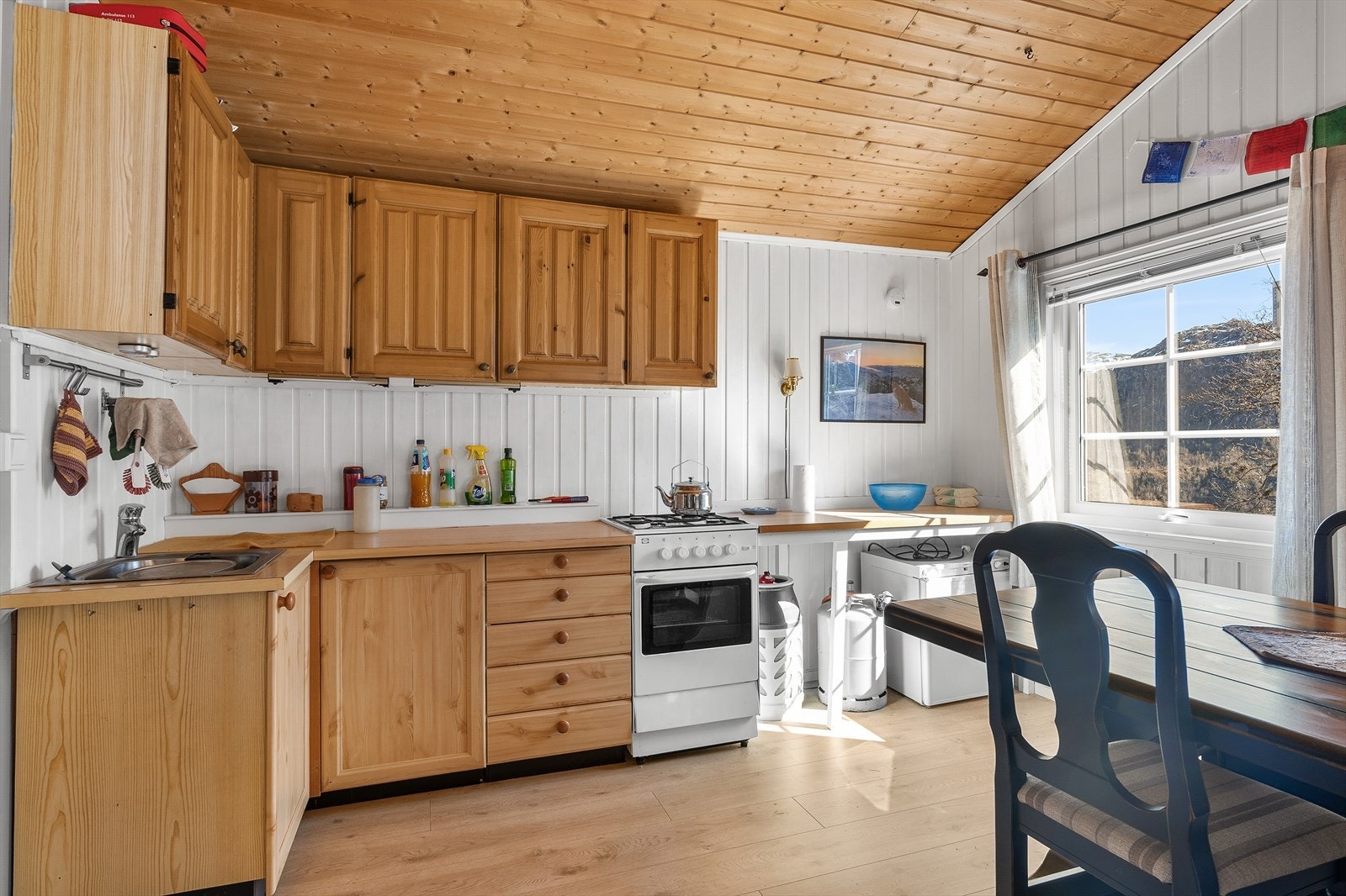 Kjøkkenet har en sjarmerende innredning i furu med laminatbenkeplate og gasskomfyr. Galleribilde