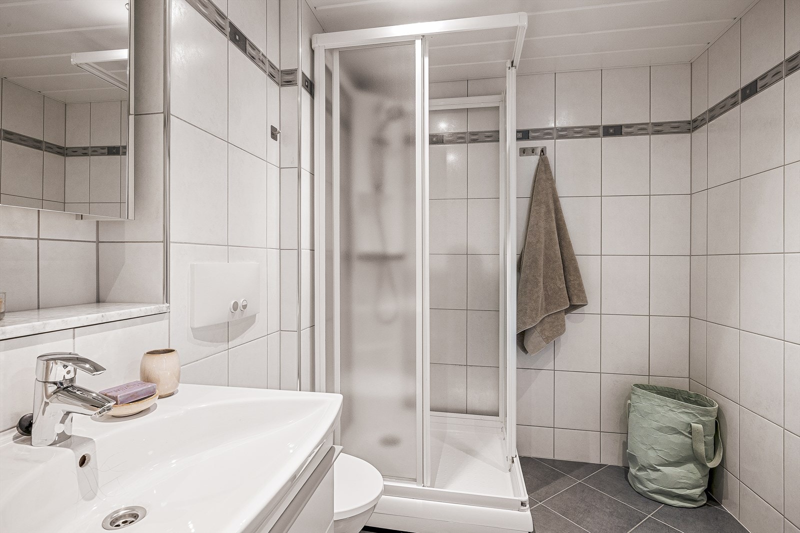 Badet er utstyrt med vegghengt toalett og dusjkabinett, som bidrar til enkel rengjøring og god plassutnyttelse. Galleribilde