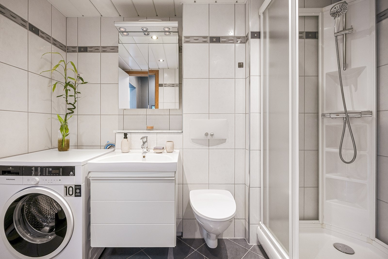Badet er på 5,5 m² og fremstår lyst og romslig med keramiske fliser på både gulv og vegger. Galleribilde