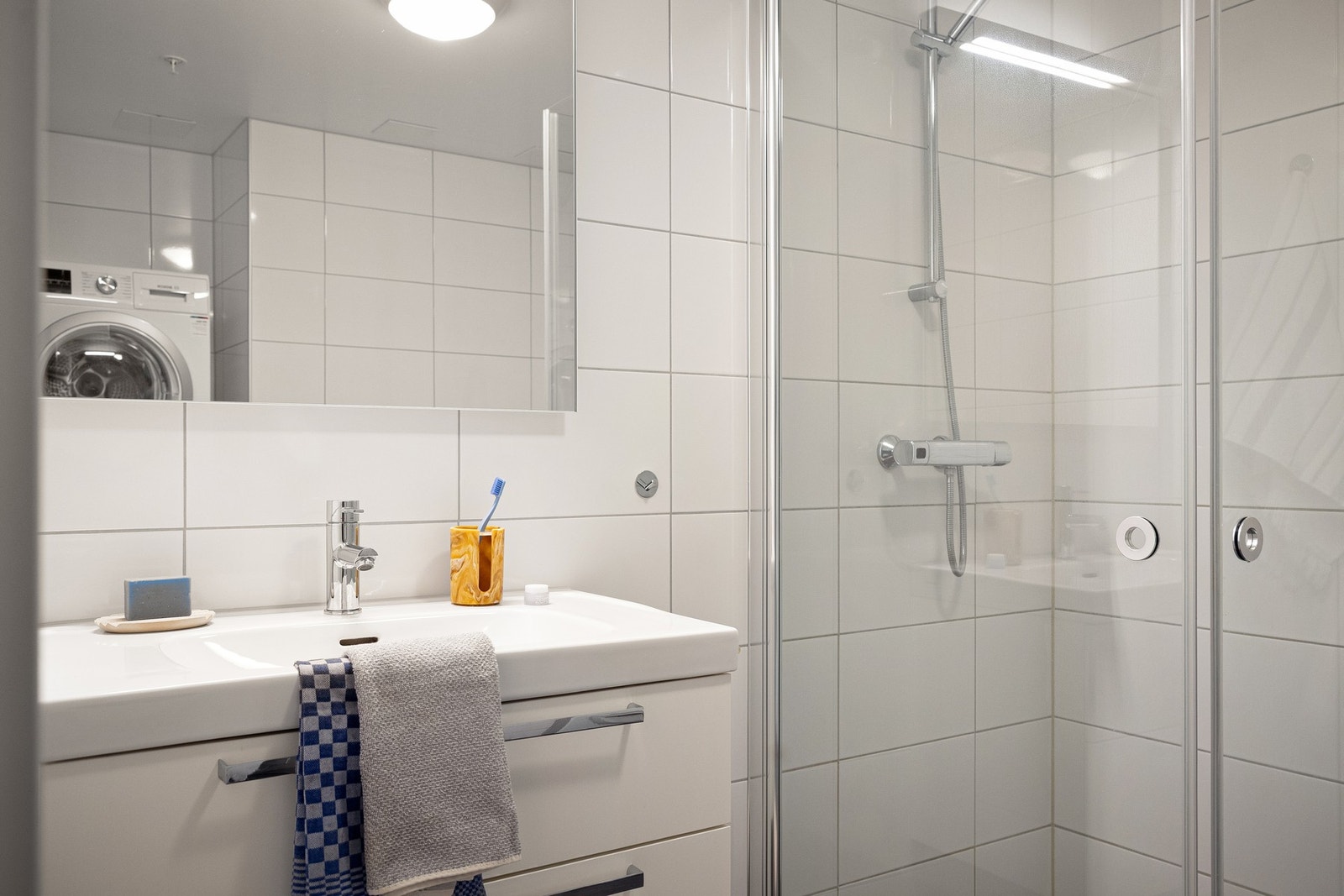 Badet er innredet med vegghengt servantinnredning med gode oppbevaringsmuligheter i skuffer, ovenpåliggende servant med ett-greps armatur samt speil med overlys. Galleribilde