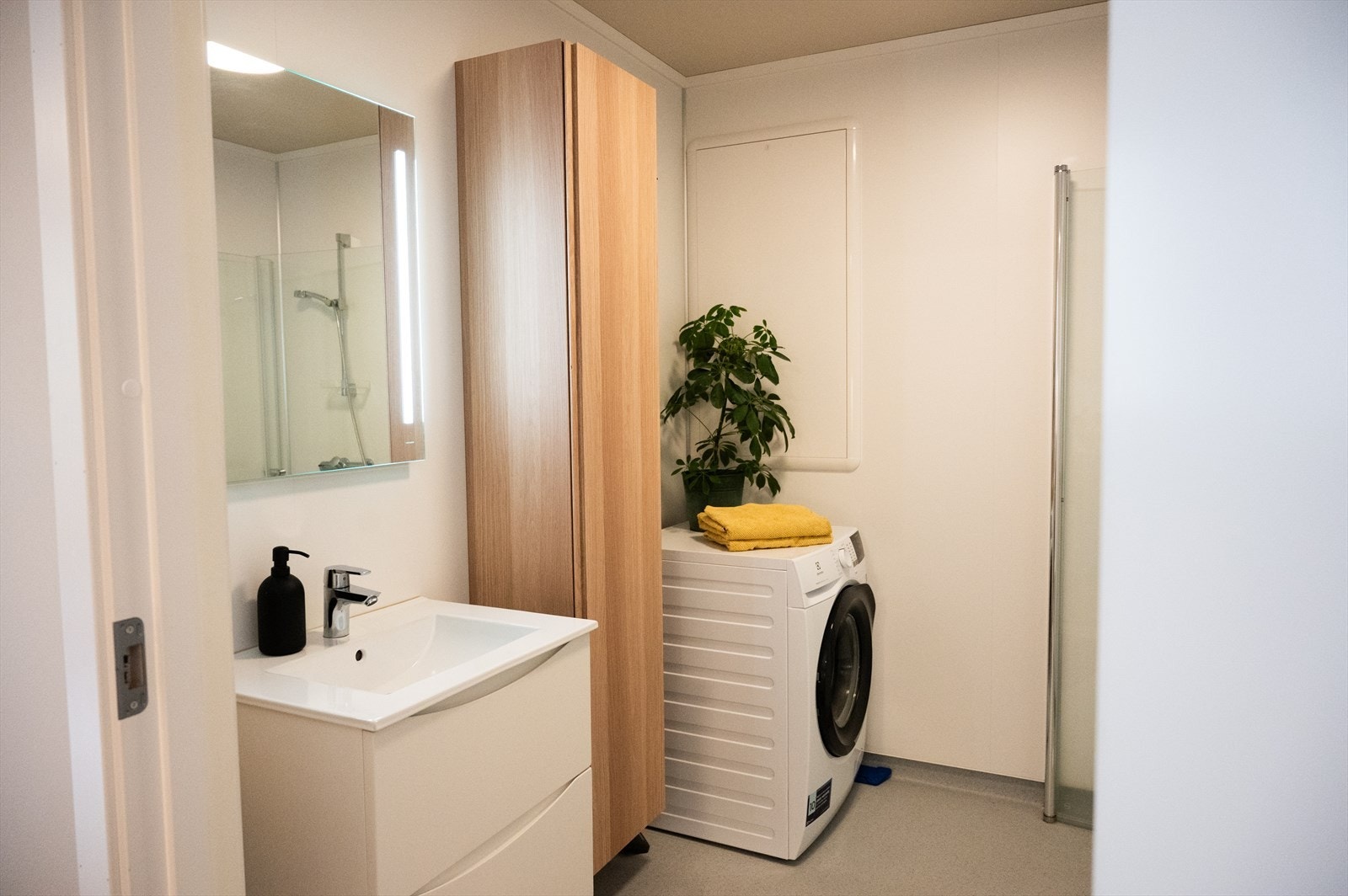 Tidlaust bad med belegg på golv og plater på vegg. Badet er innreia med lyse og stilreine servantmøblar med gode oppbevaringsmoglegheiter. Galleribilde