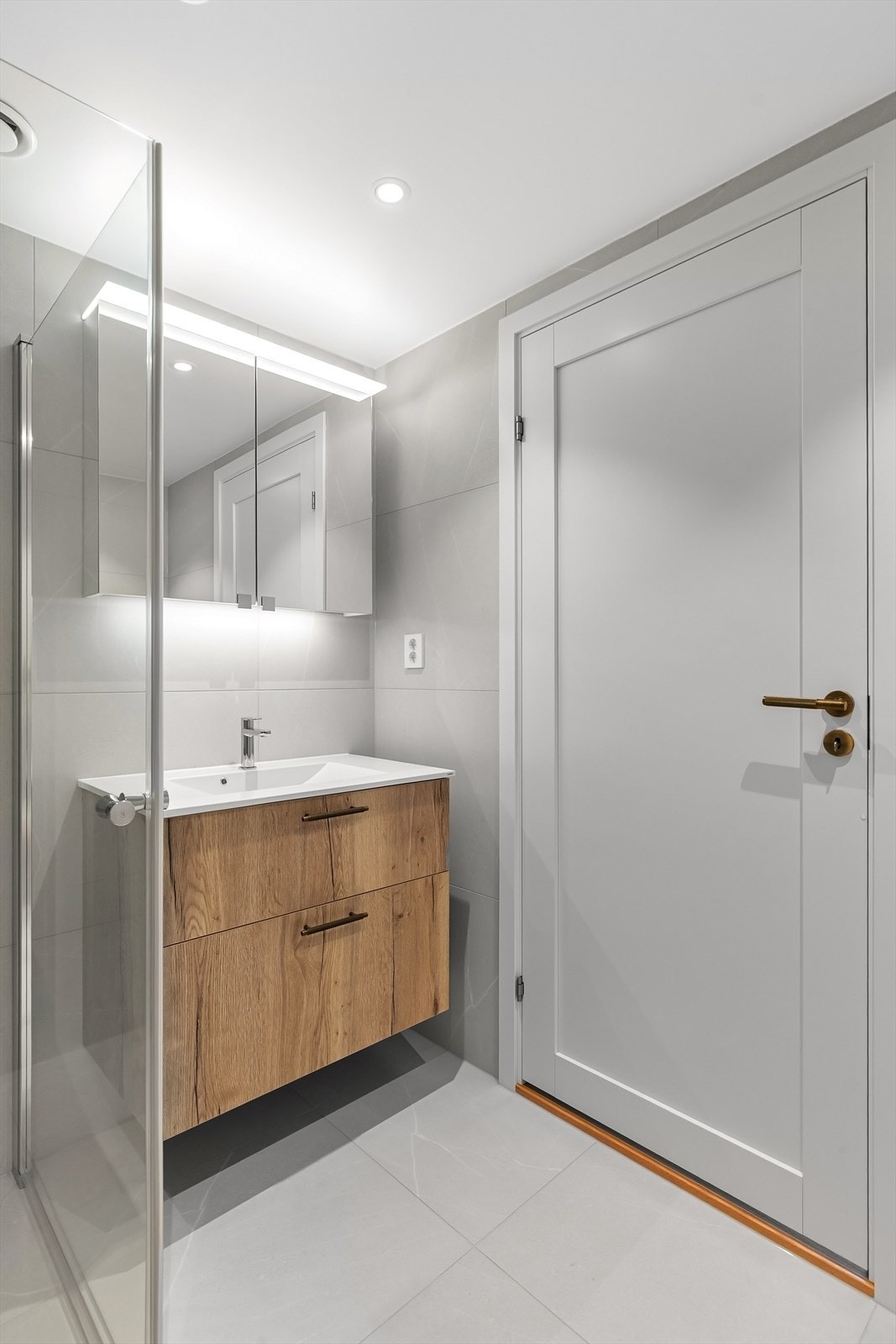 Badet er innredet med servant i underskap, speilskap med integrert lyslist, vegghengt toalett og dusjløsning med svingbare glassvegger. Galleribilde