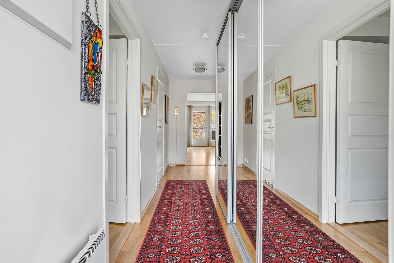 Innbydende entré og gang med god plass til yttertøy og oppbevaring. Skyvedørsgarderobe med speilfronter gir praktiske oppbevaringsmuligheter samtidig som speilene bidrar til en lys og romslig følelse Galleribilde