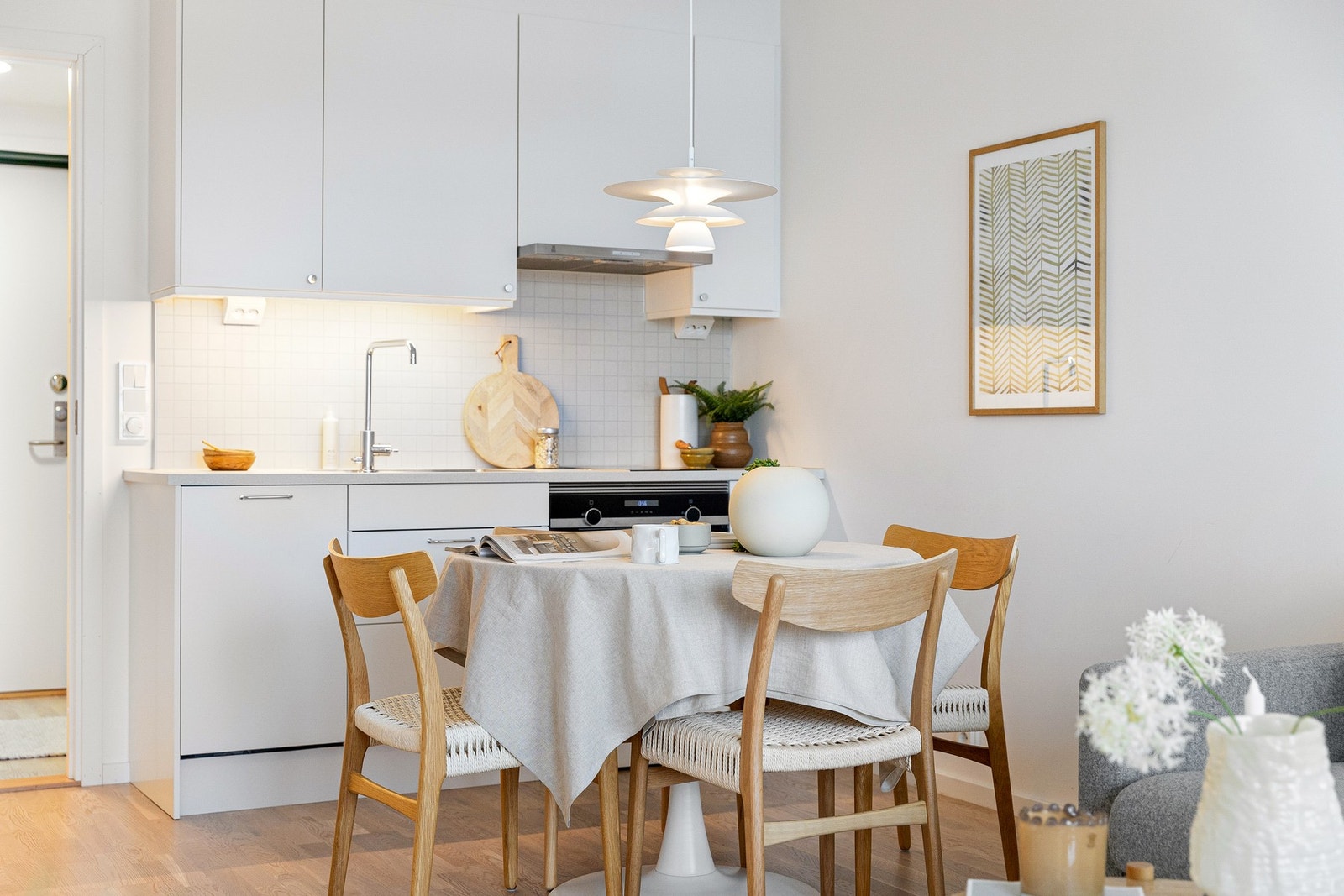 Kjøkkeninnredningen er utstyrt med hvite glatte fronter, benkeplate i laminat med nedfelt kum i rustfritt stål og belysning under overskap. Galleribilde