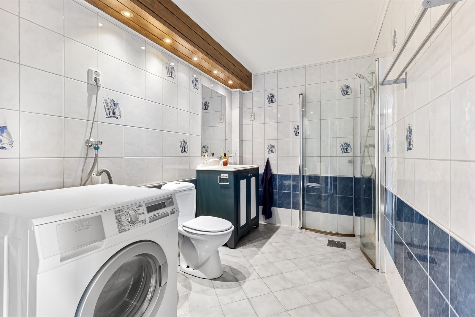 Badet har flislagt gulv med gulvvarme, dusjhjørne og opplegg for vaskemaskin. Galleribilde