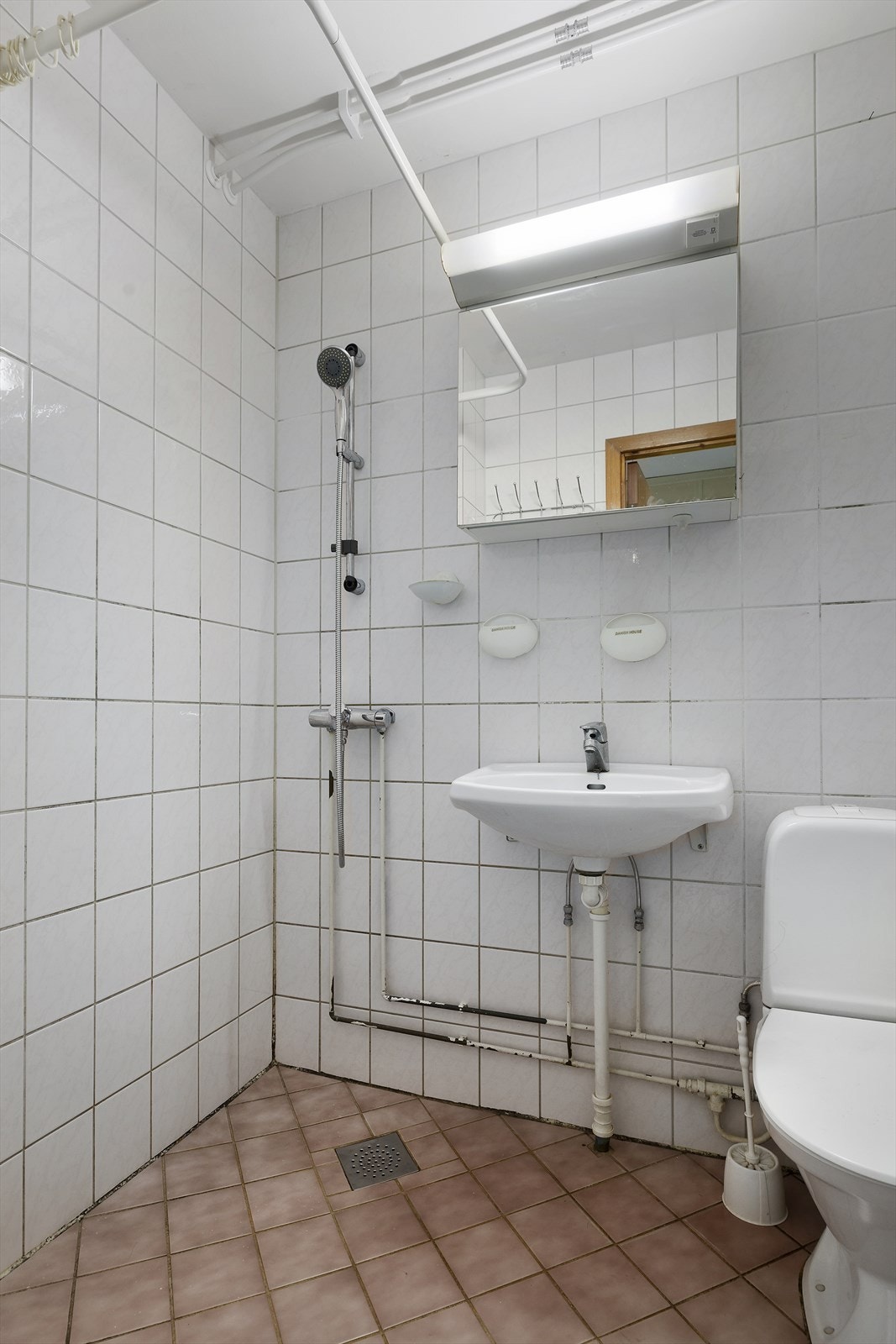 Baderommet har i dag en innredning bestående av gulvmontert toalett, servant og dusjhjørne Galleribilde