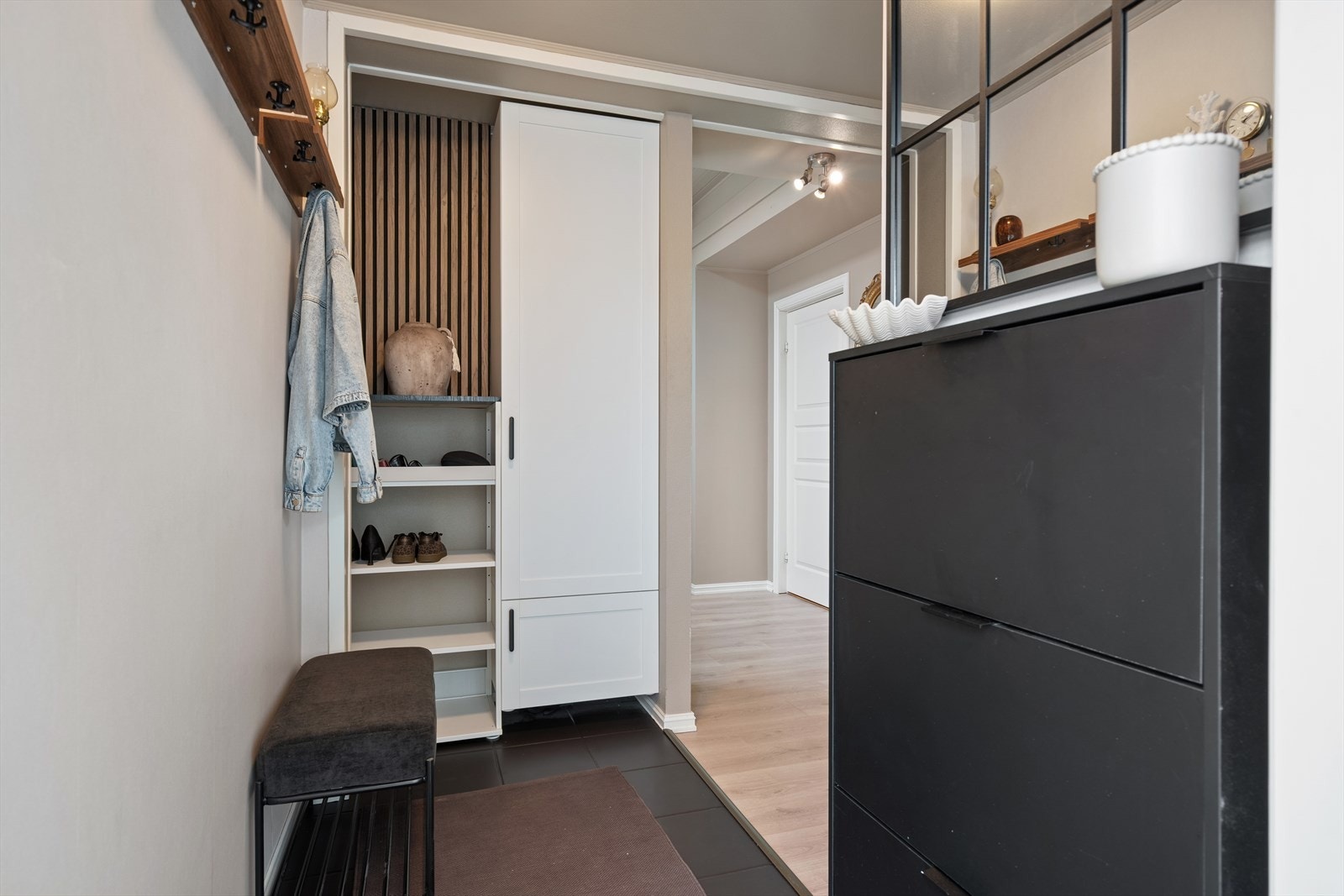 Her ønskes man velkommen inn i en praktisk entré med plass til skohylle og opphengsløsning, samt et vegghengt garderobeskap som gir gode oppbevaringsmuligheter. Galleribilde