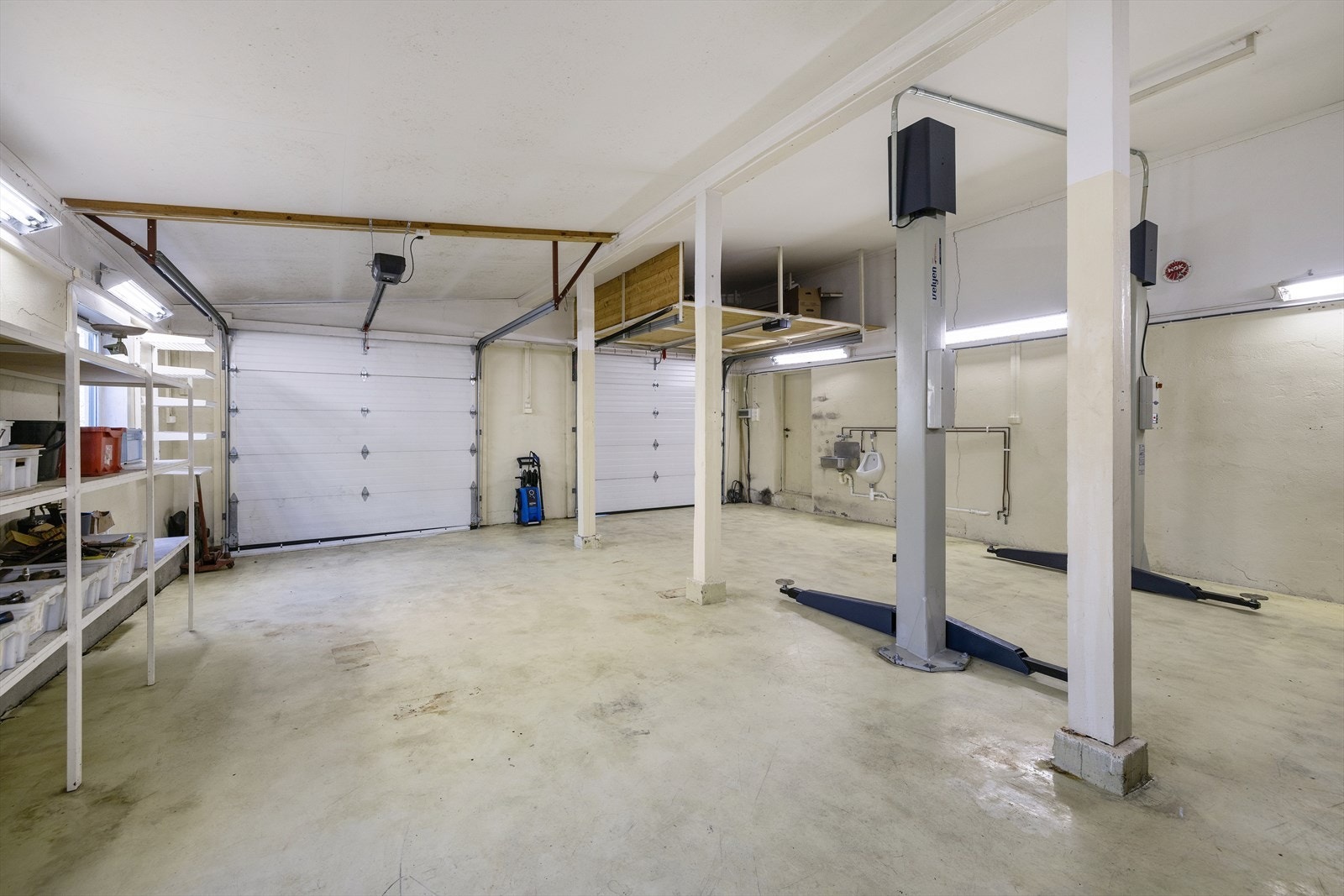 Garasjen har god takhøyde, to garasjeporter og installert løftebukk. Galleribilde