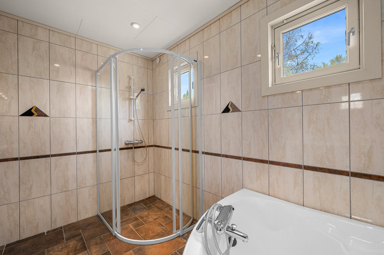 Badet måler 7 kvm og er innredet med servantskap med speil og lys, badekar og dusjhjørne. Galleribilde