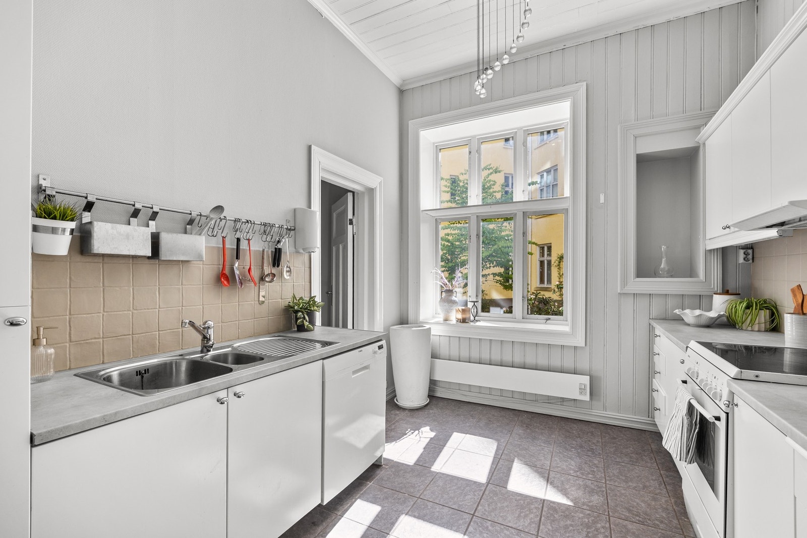 Kjøkkeninnredning med slette hvite fronter, laminat benkeplate og stålkum Galleribilde