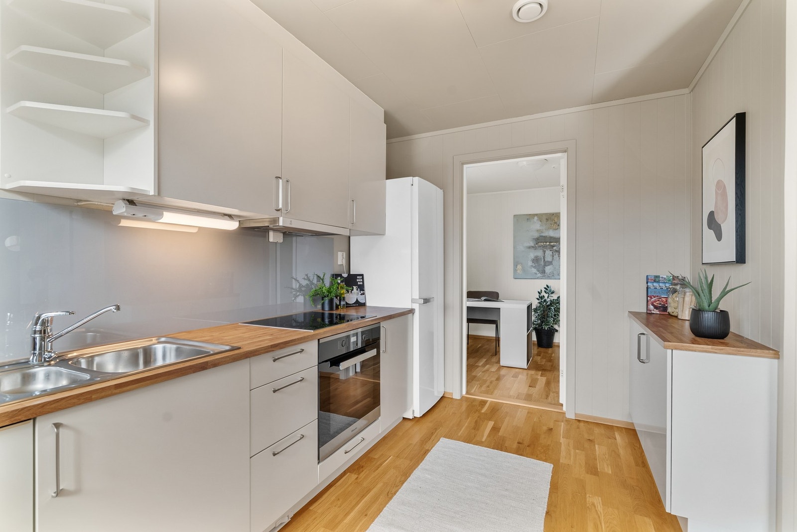 Kjøkkeninnredning med laminatbenkeplate, nedfelt komfyrtopp, steketopp og integrert oppvaskmaskin. Frittstående kjøleskap følger med. Galleribilde