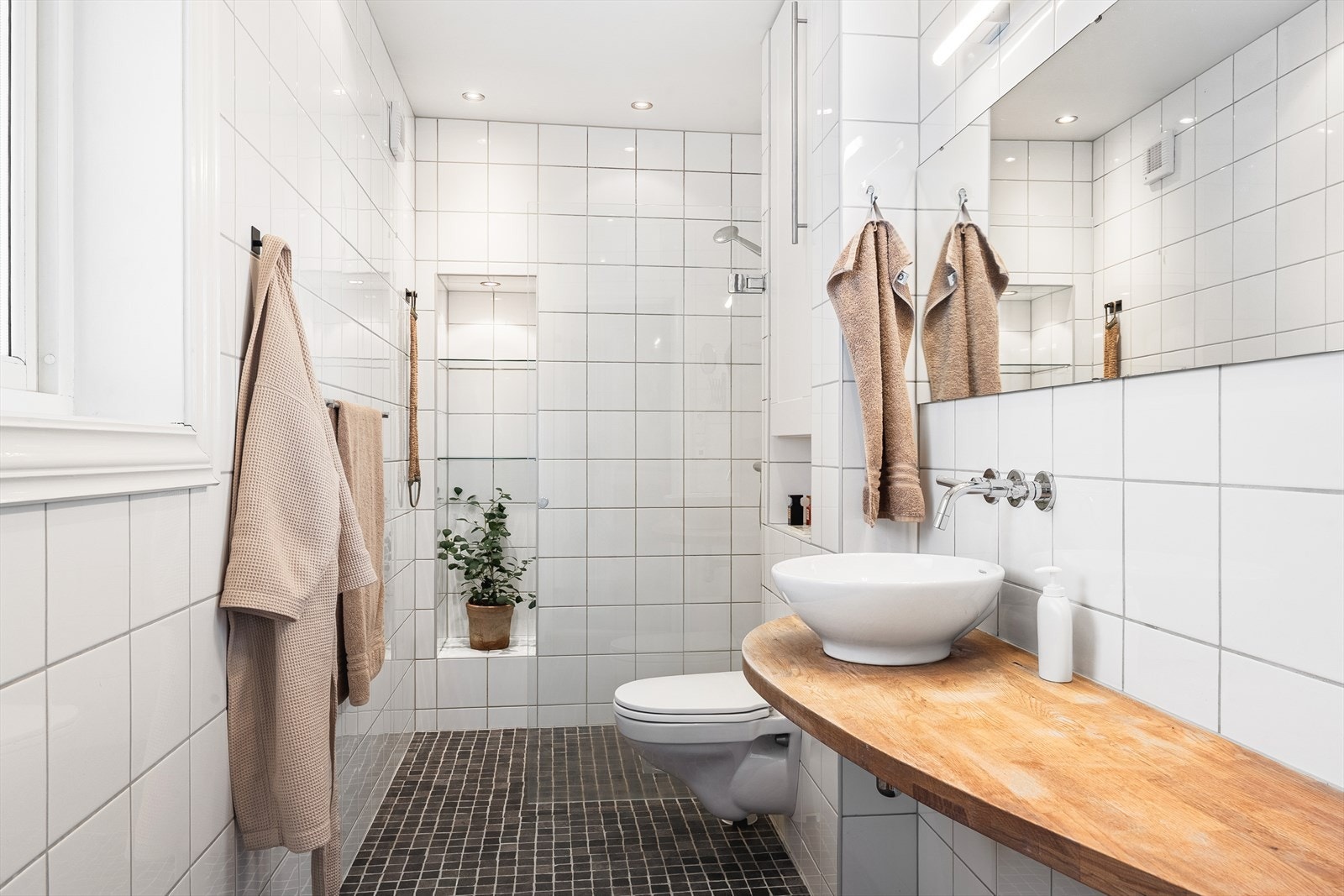 Badet er av god størrelse og inneholder benkeplate med servant, vegghengt toalett og dusj Galleribilde