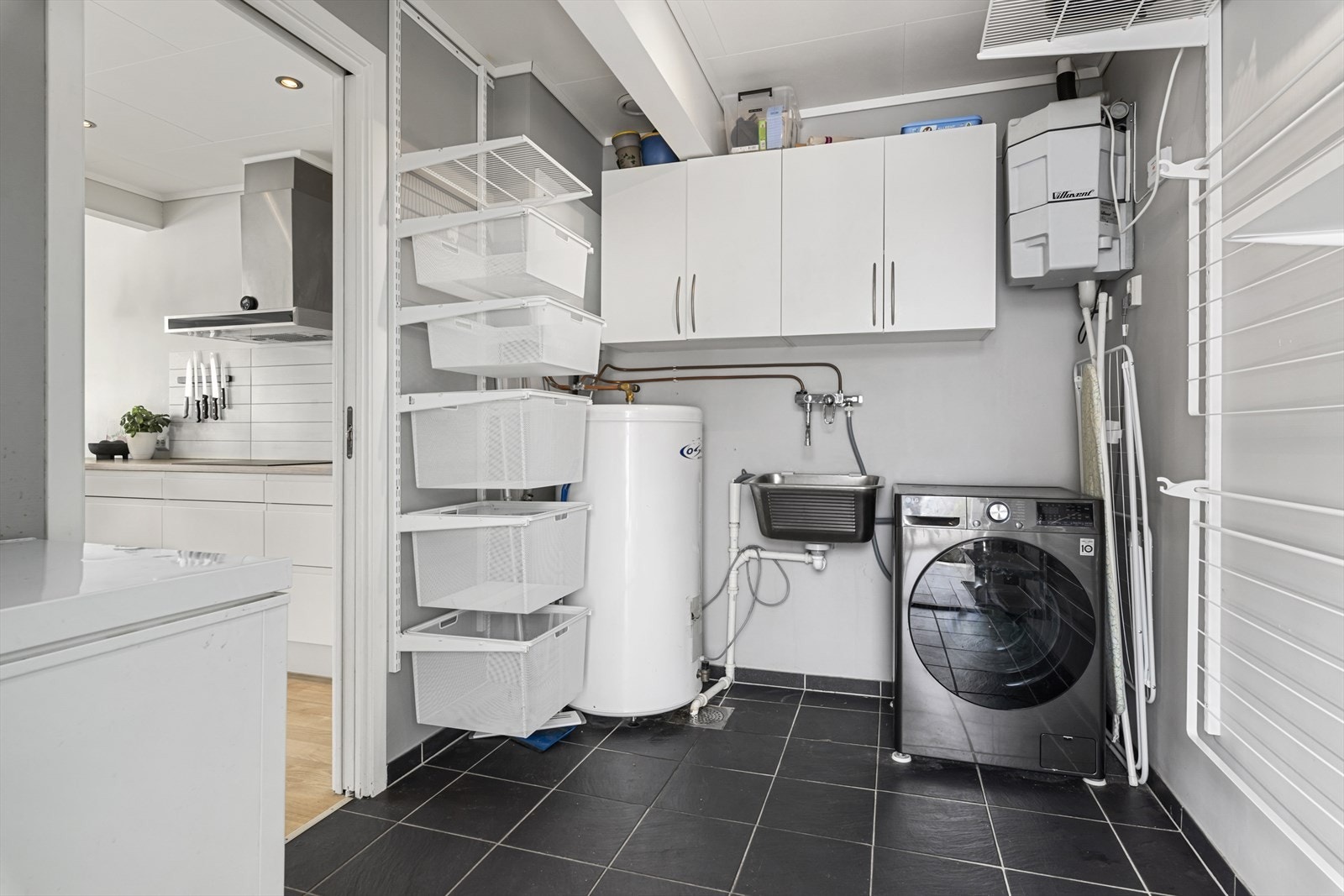 Vaskerommet har fliser på gulvet, opplegg for vaskemaskin og tørketrommel, skyllekar og avtrekk til balansert ventilasjonsanlegg. Galleribilde