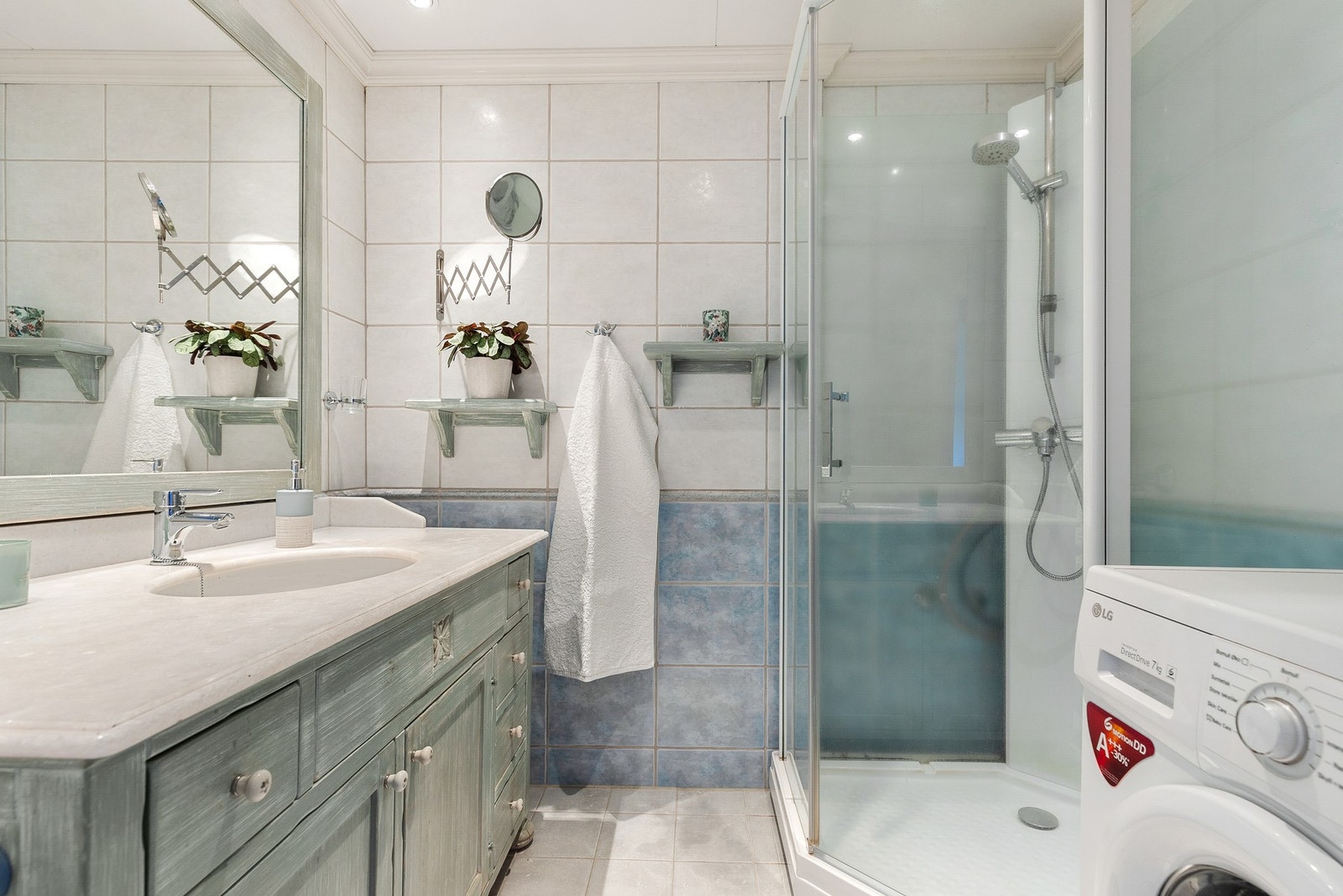Badet er utstyrt med gulvstående servantinnredning med ovenpåliggende servant med armatur og speil Galleribilde