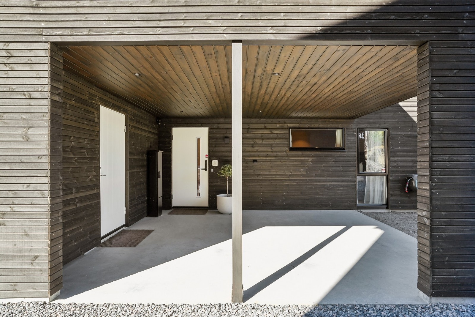 Overbygd inngangsparti med støpt betongplate på grunn, og direkte tilkomst til carport. Utvendig vannutkaster. Galleribilde