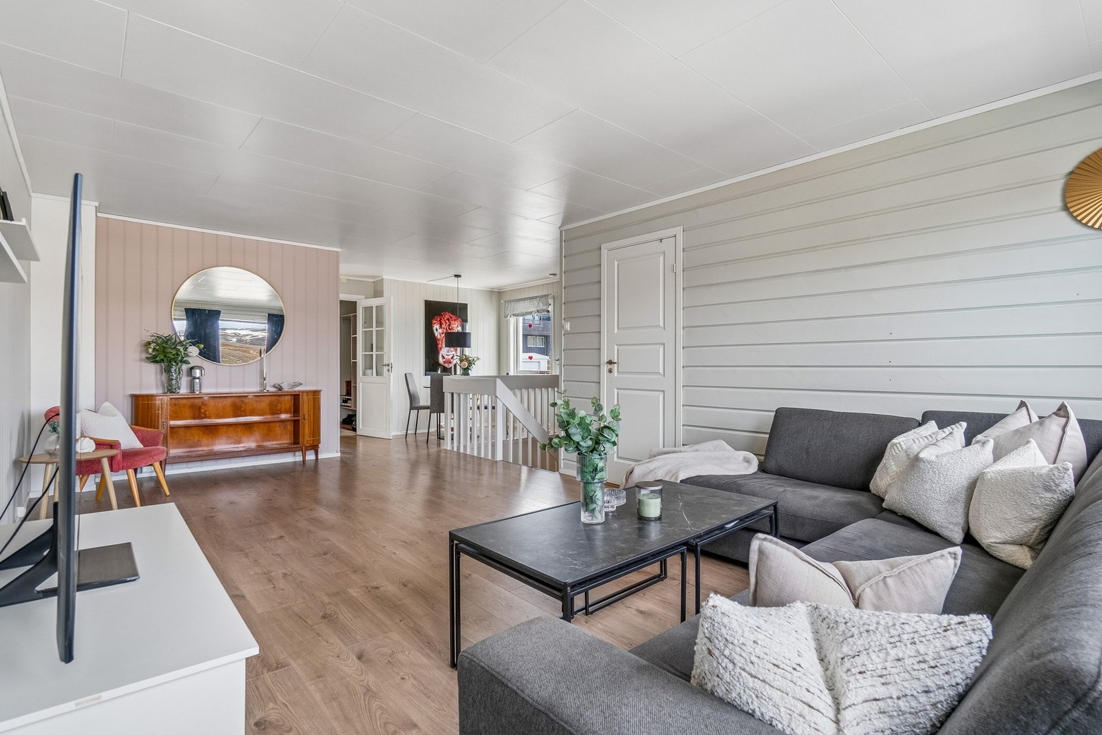 Stuen gir et tidløst inntrykk med lyse fargevalg, og her finner du det ene soverommet og adkomst til boligens balkong. Galleribilde