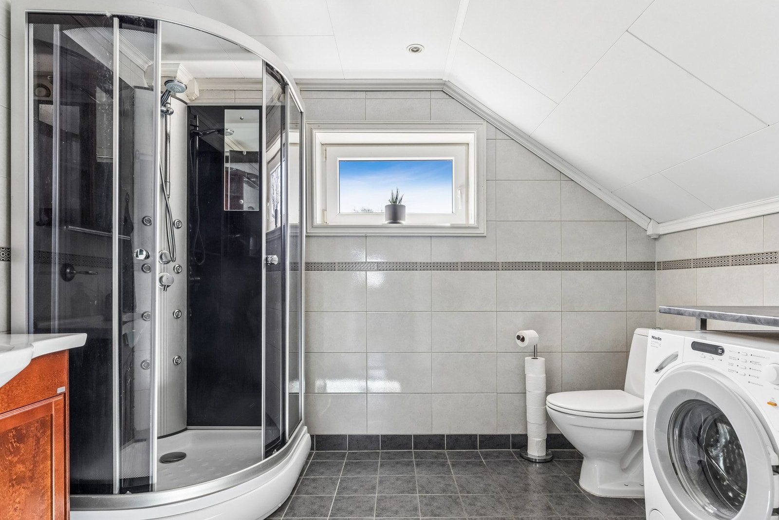Badet ligger i loftsetasjen og byr på flislagte overflater og en praktisk planløsning. Galleribilde