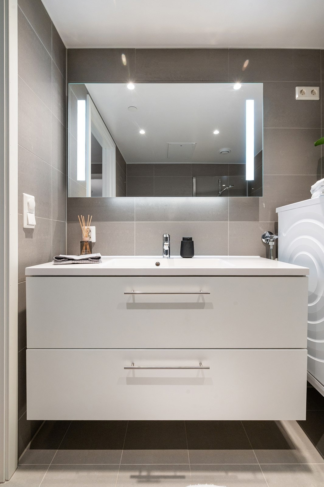 Vegghengt speil med belysning samt vegghengt toalett. Badet har opplegg for vaskemaskin og tørketrommel, og er utstyrt med balansert ventilasjon. Galleribilde