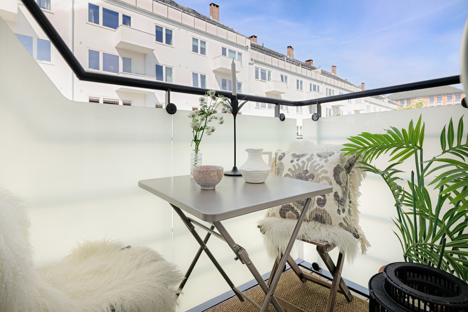 Balkongen er overbygget, har terrassebord på gulv og rekkverk med frostet glass. Galleribilde