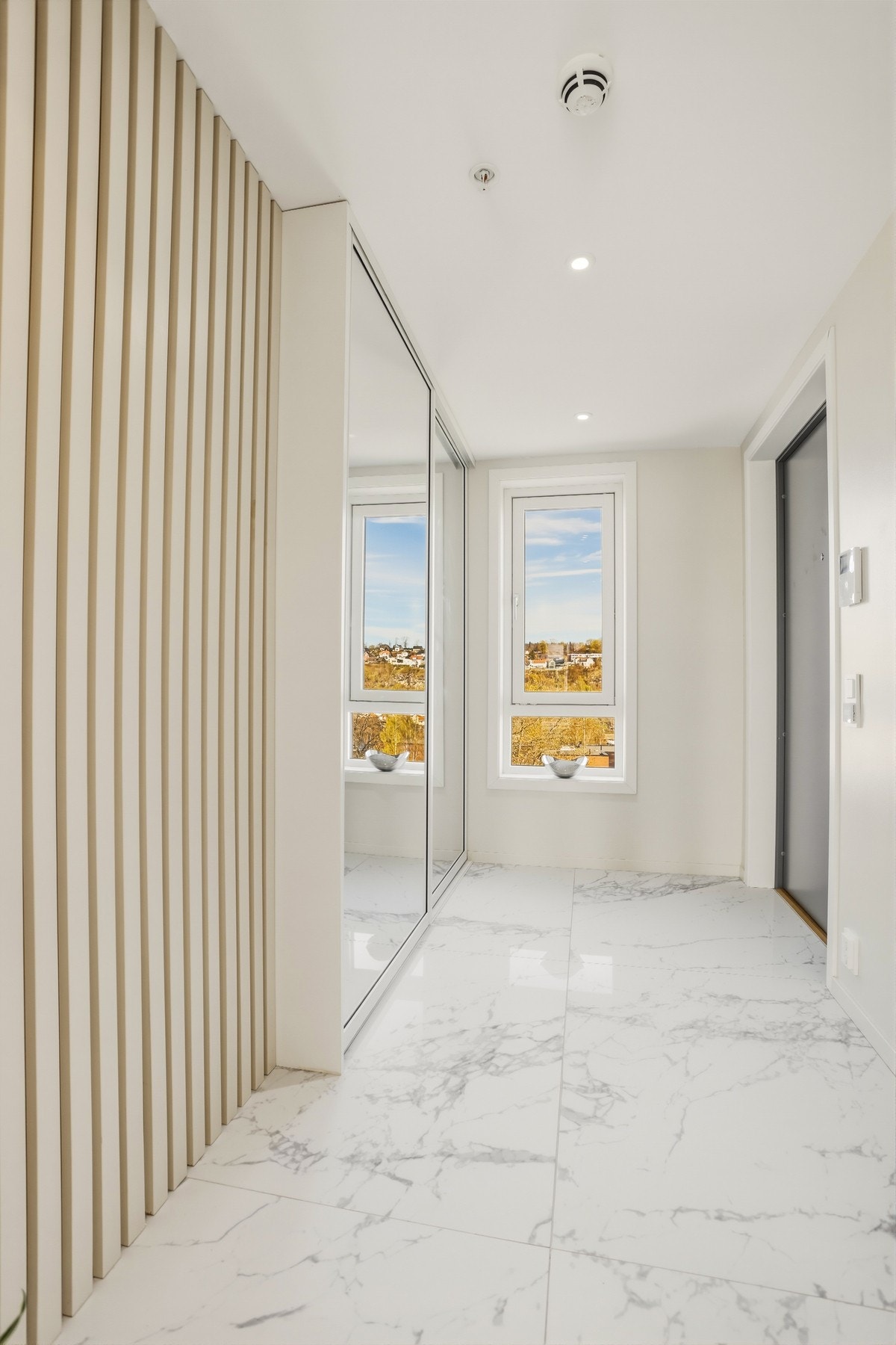 I entreen er det både gulvvarme og en stor skyvedørsgarderobe, og i den hvite himlingen er det downlights. Hele leiligheten fremstår i duse, delikate farger og med meget høy standard. Galleribilde