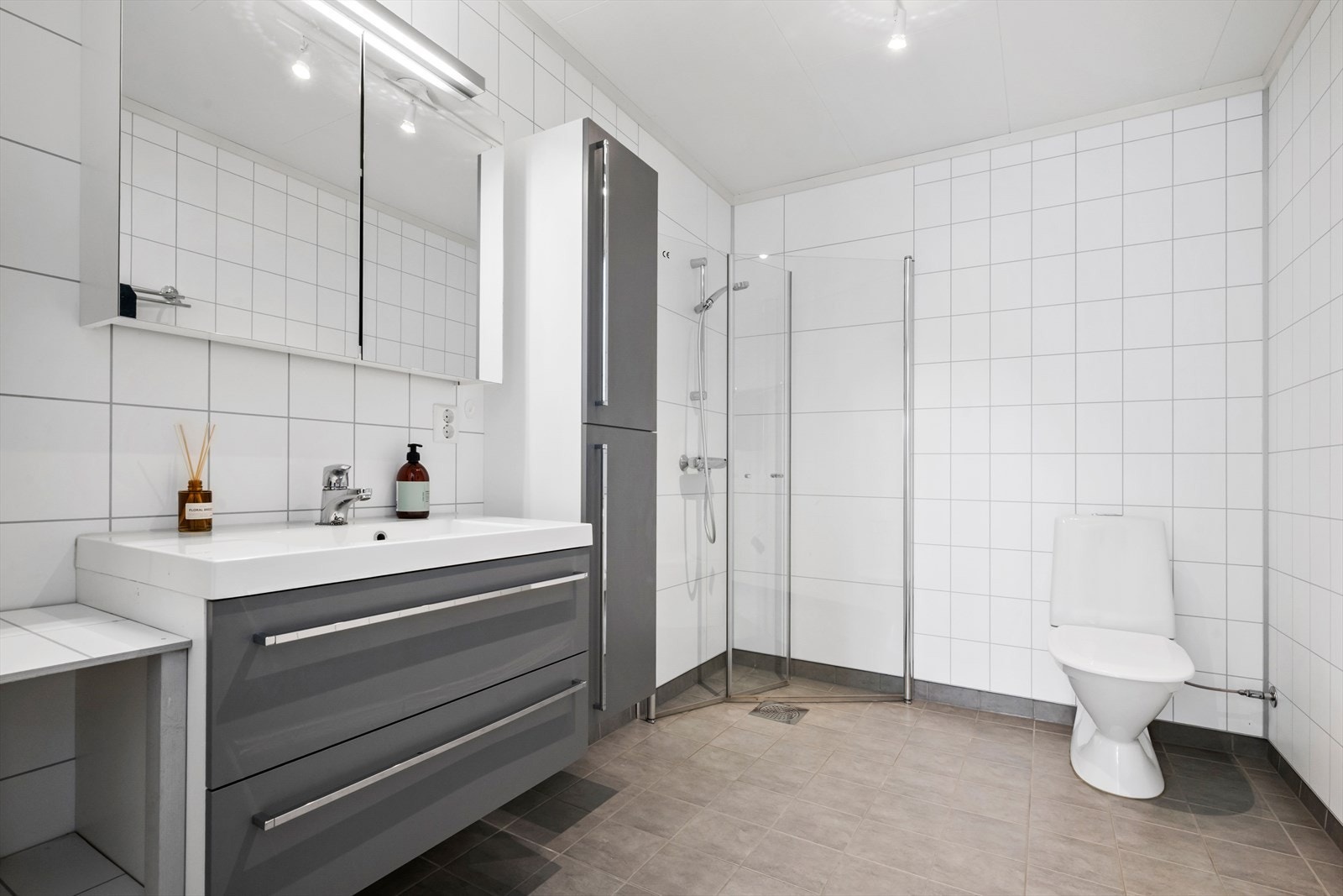 Lyst og fint bad som er innredet med toalett, dusjdører og innredning med servant. Galleribilde
