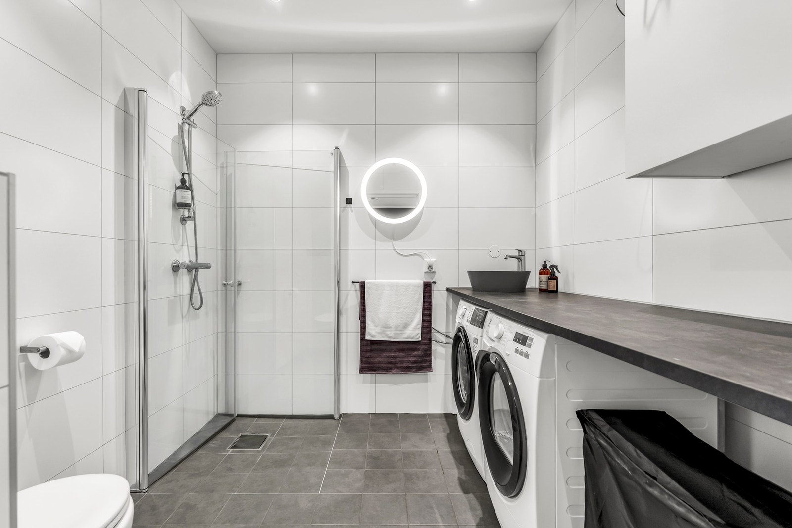 Badet/vaskerommet nede har en lang arbeidsbenk med toppmontert servant og nisje til vaskemaskin og tørketrommel. Galleribilde