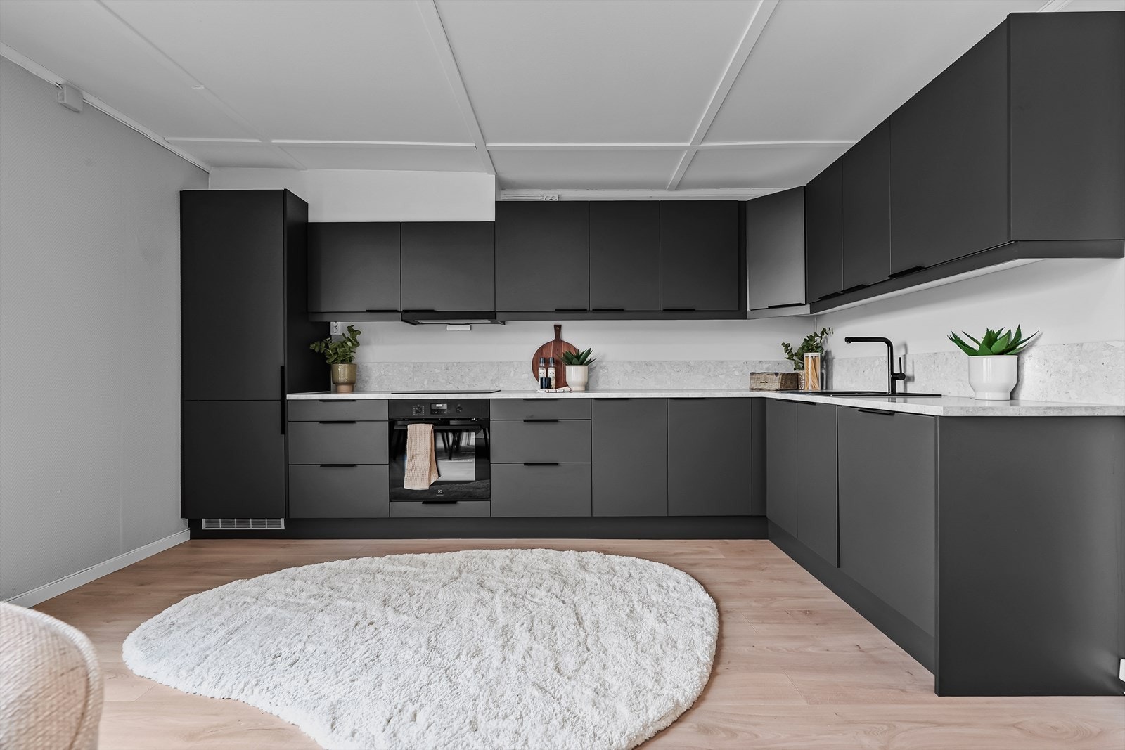 Stilrent kjøkken fra Sigdal med slette fronter og overskap som gir et moderne og tidløst uttrykk. Lys laminatbenkeplate med nedfelt komposittvask og sort ett-greps armatur. Galleribilde