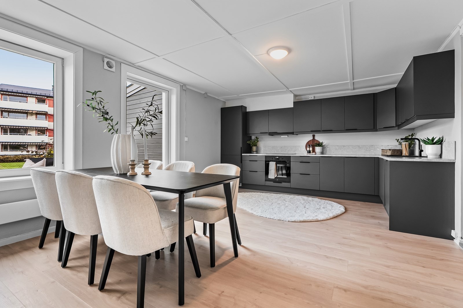 Gjennomgående plan med åpen kjøkkenløsning og spiseplass. Moderne mørke fronter, lys benkeplate og god tilgang til dagslys gjennom store vindusflater. Galleribilde