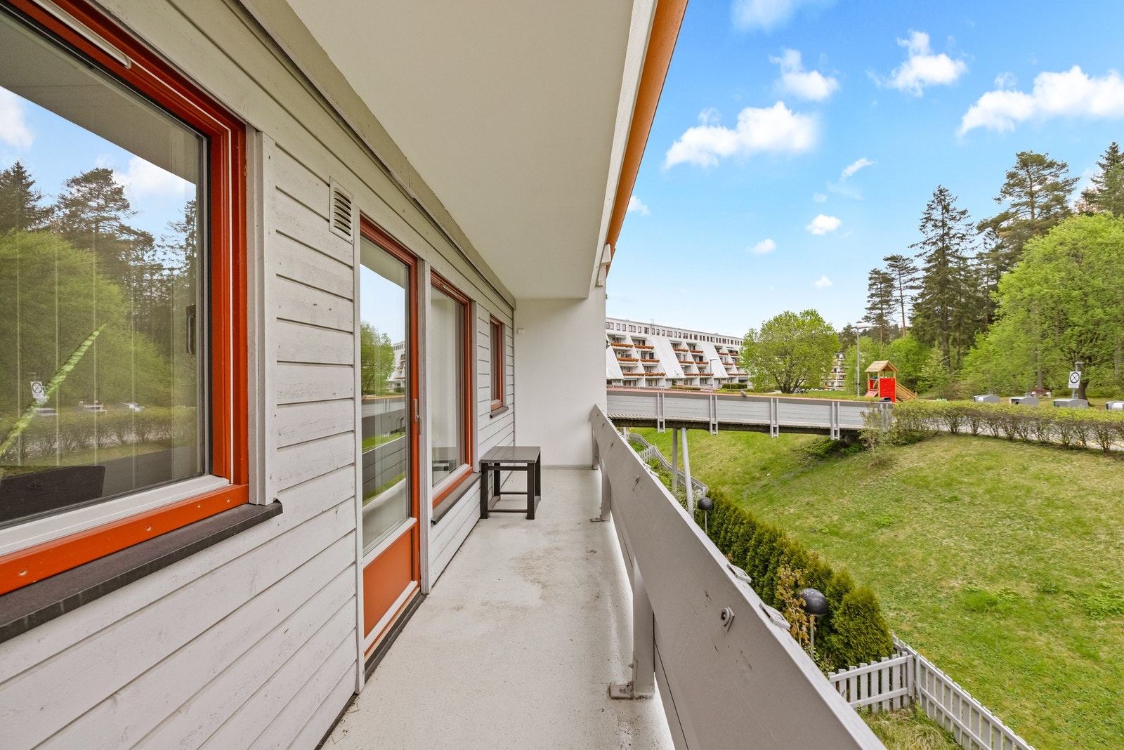 Balkong på motsatt side av boligen med utsyn mot grønne fellesarealer og nærliggende lekeplass. Galleribilde