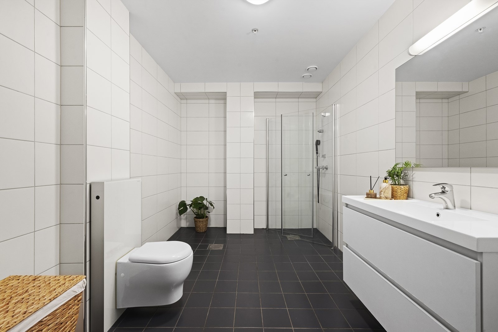 Hovedbadet er flislagt og inneholder vegghengt toalett, servantinnredning og dusjvegg. Galleribilde