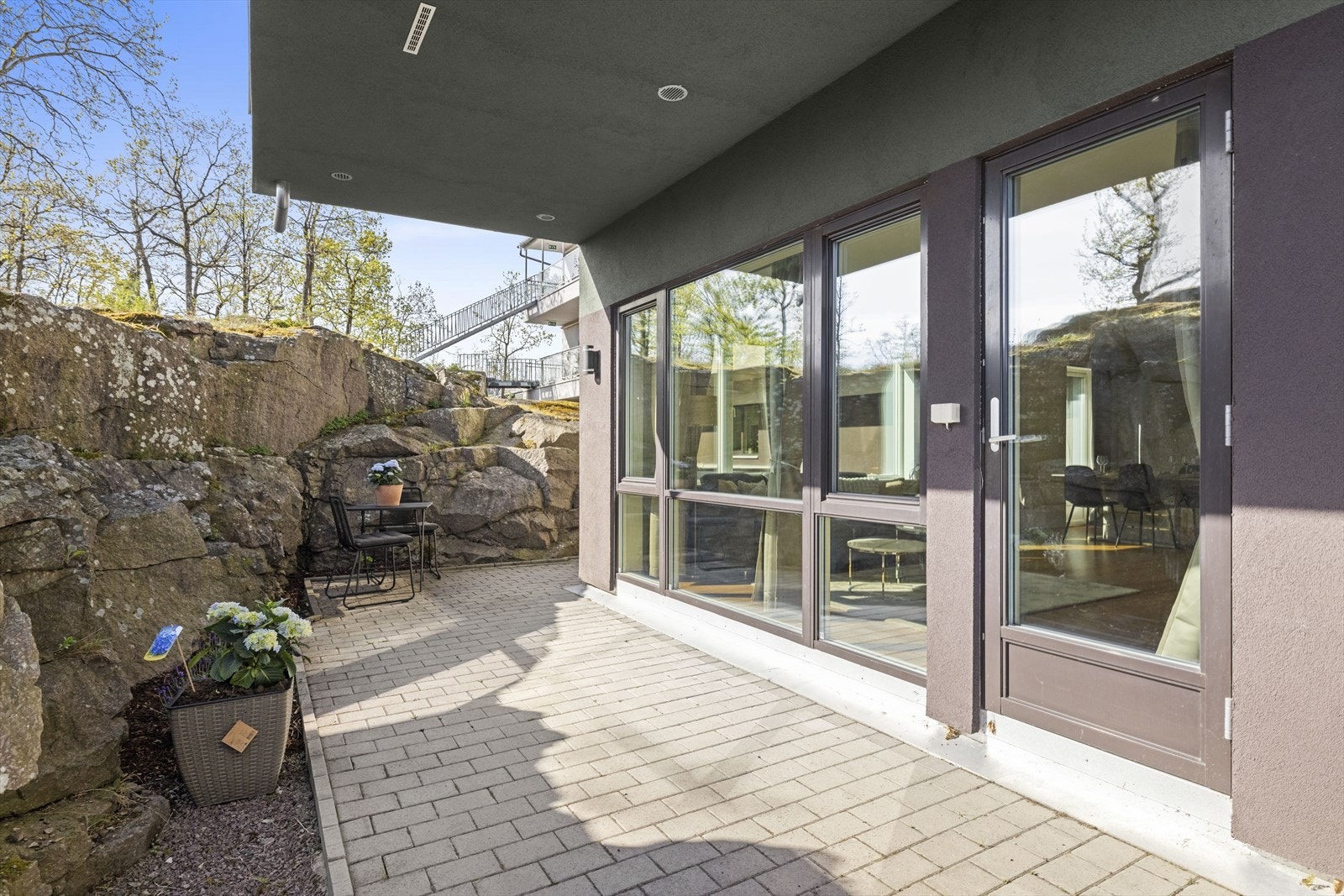 Den steinsatte uteplassen oppleves som lun og hyggelig, og ligger i direkte tilknytning til stuen, noe som gir en sømløs overgang mellom inne- og uteplass. Galleribilde