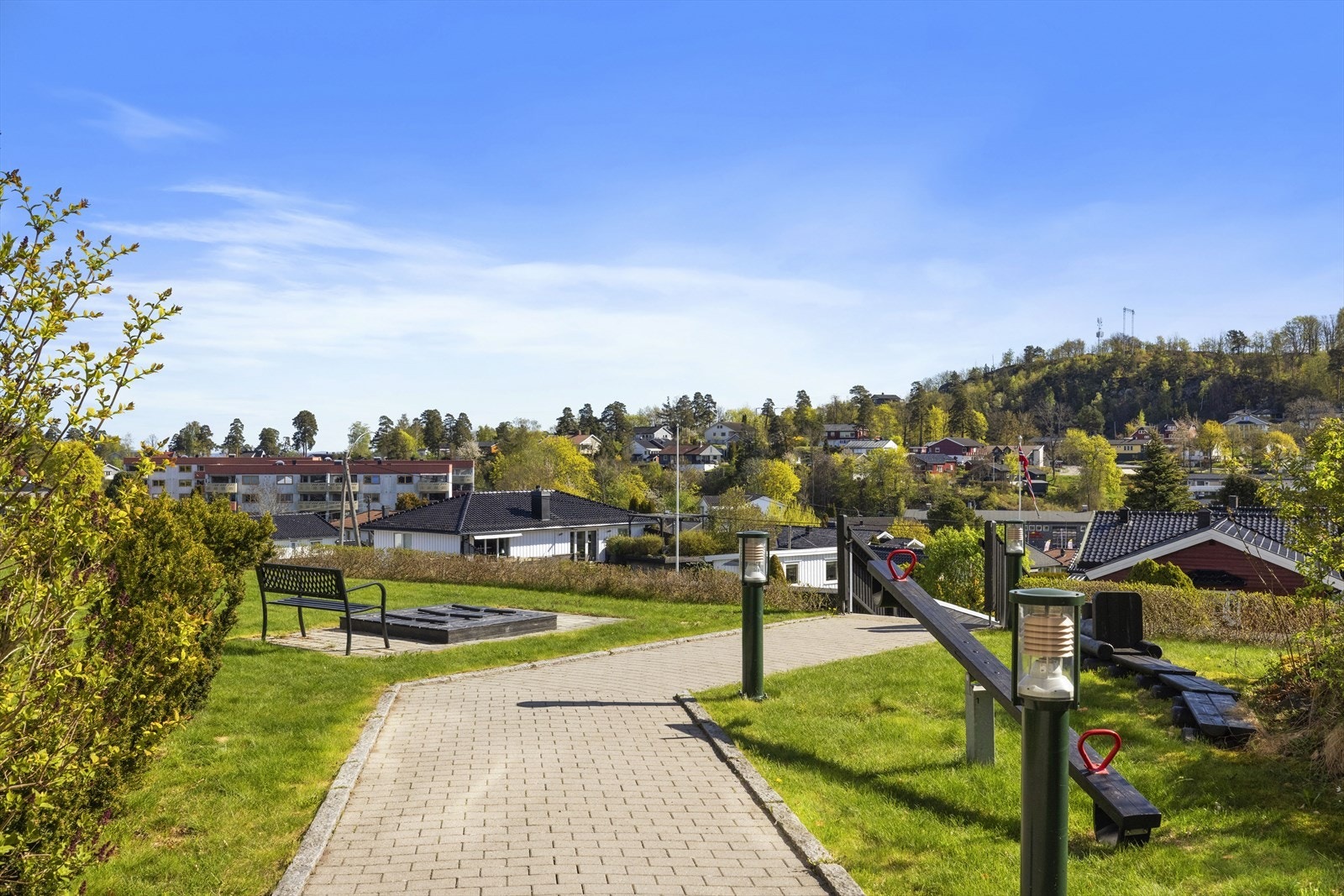 Stor felles gressplen foran bygningen mot øst med sandkasse og uteplass med hagemøbler til felles bruk. Galleribilde