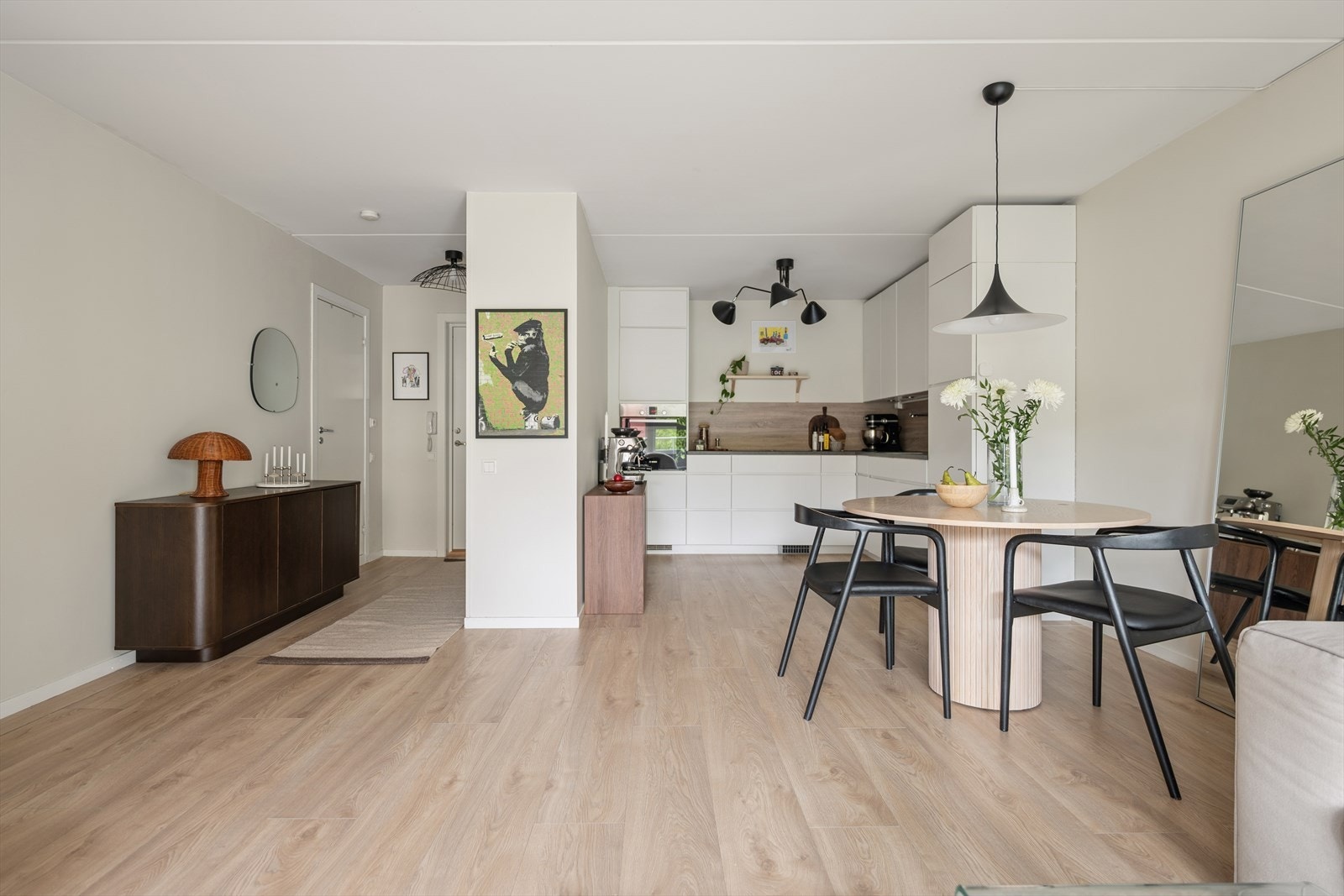 Kjøkkenet ligger i åpen løsning mot stue og spiseplass, men er samtidig trukket tilbake i rommet og oppleves som en egen, skjermet sone. Galleribilde