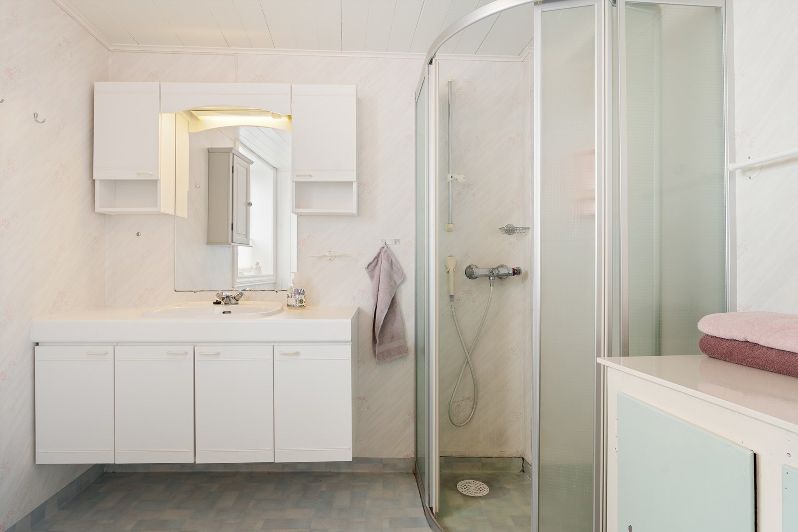 Badet i underetasjen har vinylbelegg på gulv, våtromstapet på vegger og panel i himling - rommet vurderes å ha behov for oppgradering for å tilfredsstille dagens krav til normal bruk Galleribilde