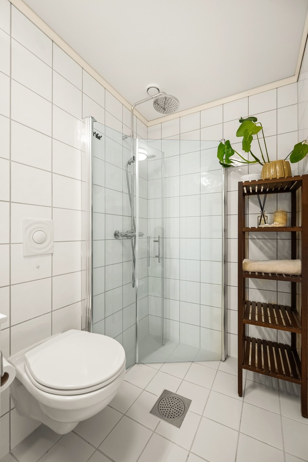 Badet er innredet med vegghengt toalett, servant i innredning, speilskap med belysning og dusjhjørne med svingbare glassdører. Galleribilde