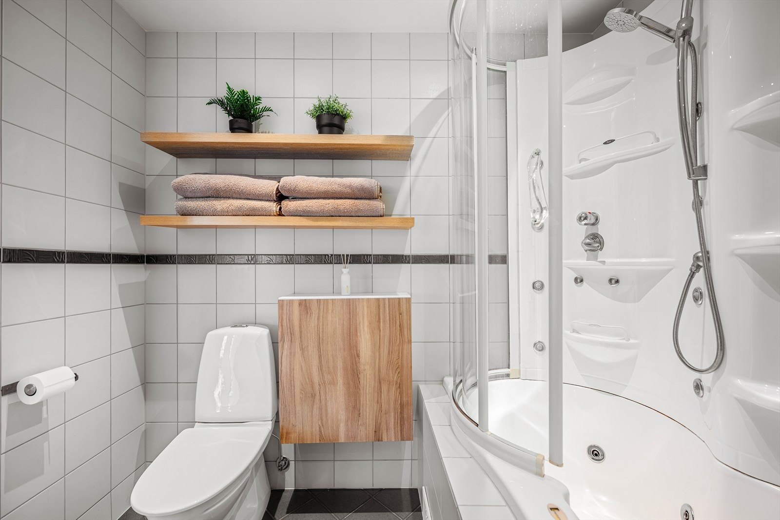 Badet er innredet med toalett, vask i seksjon med oppbevaring, badekar med dusjmuligheter. Galleribilde