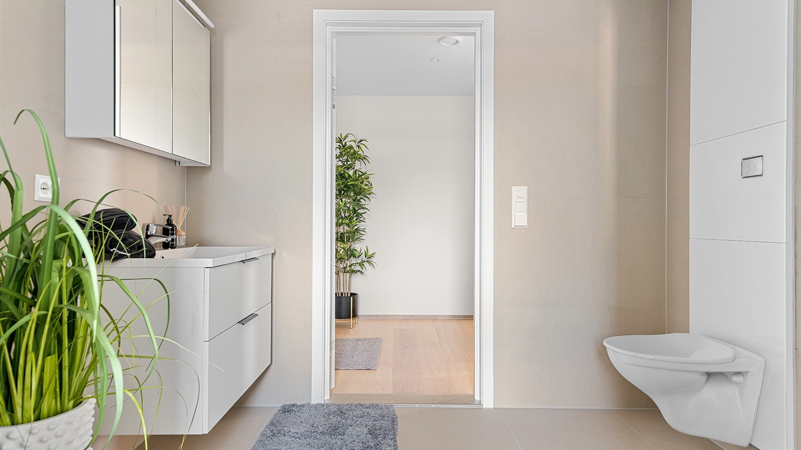 Badet har lys og fin innredning med vegghengt toalett, innfellbare dusjvegger, og servant med skuffeseksjon, samt speilskap ovenfor. Galleribilde